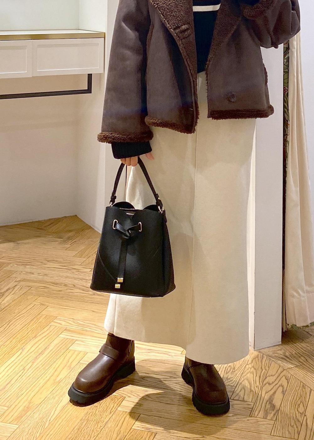 ブラック系のショルダーバッグ、ブラウン系のブーツ、ブラック系のニット/セーターを着用したレディースの秋コーディネートの4枚目の写真