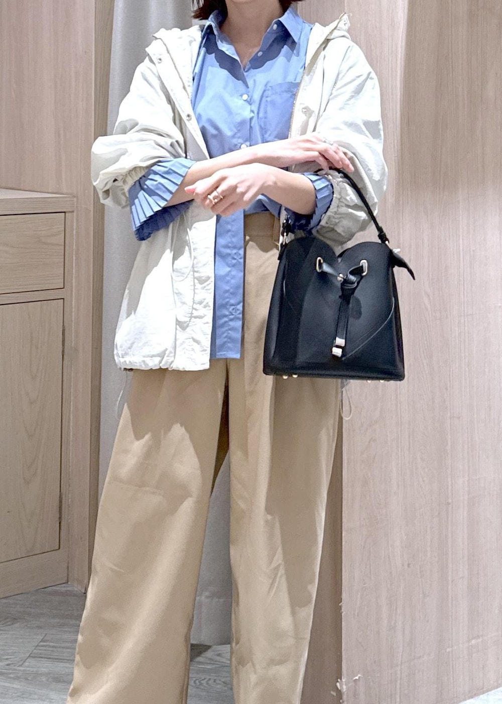 ブラック系のショルダーバッグ、ホワイト系のマウンテンパーカー、ブルー系のシャツ/ブラウスを着用したレディースの春コーディネートの6枚目の写真