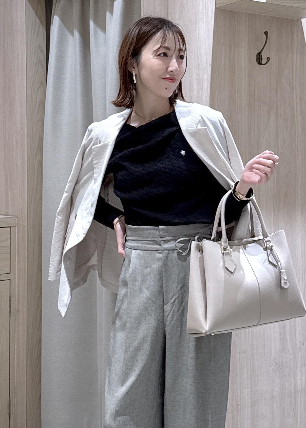 ブラック系のパンプス、グレー系のその他パンツ、ホワイト系のテーラードジャケットを着用したレディースの春コーディネートの2枚目の写真