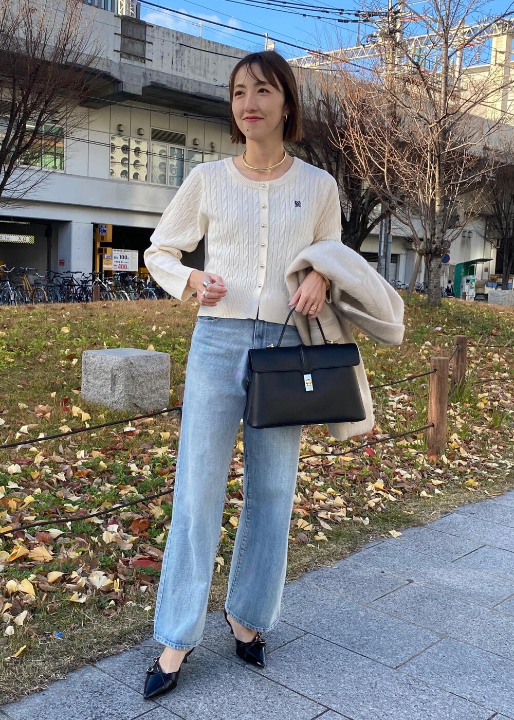 ブラック系のパンプス、ホワイト系のカーディガン/ボレロ、ベージュ系のその他アウターを着用したレディースの冬コーディネートの2枚目の写真