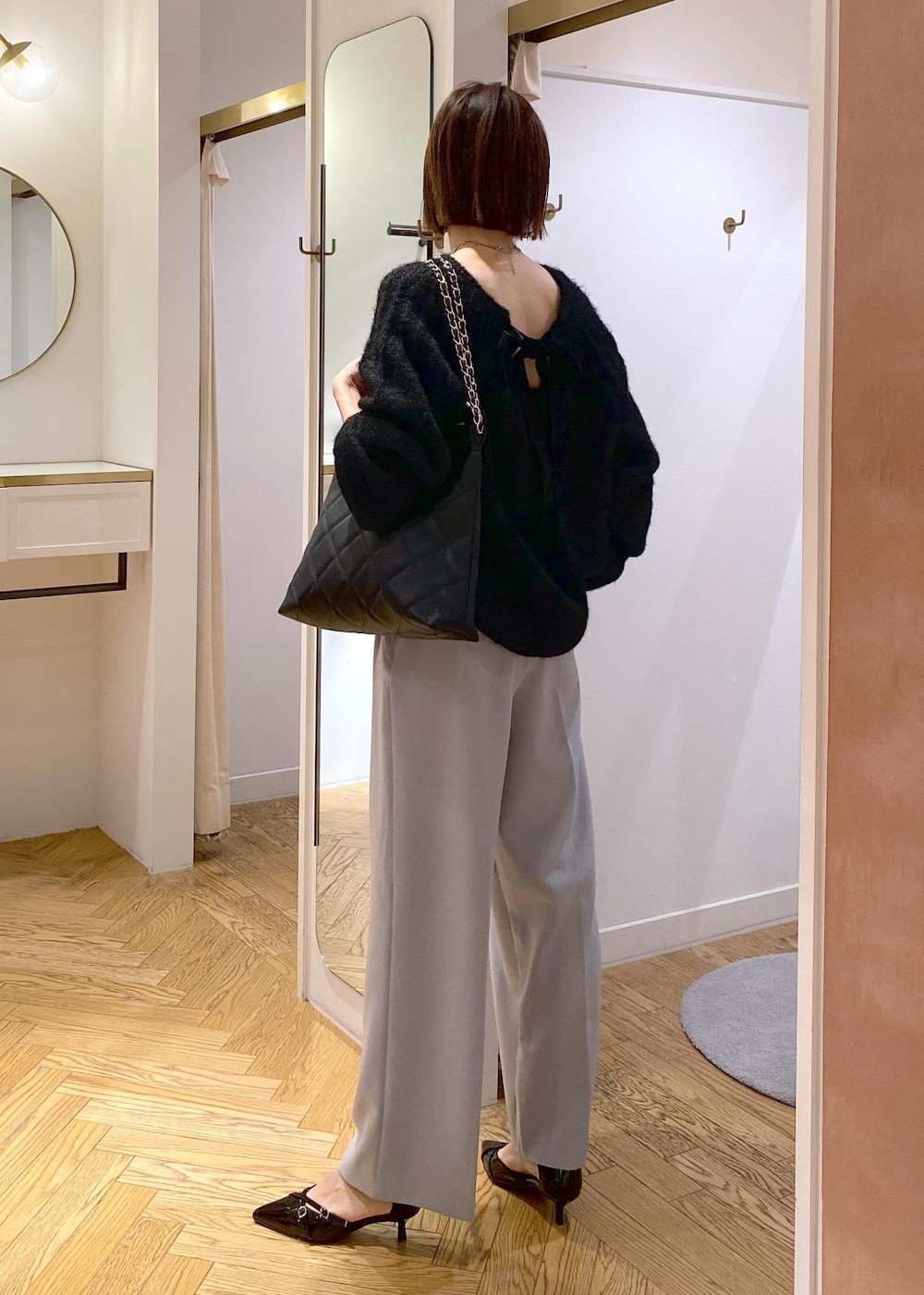 ブルー系のスラックス、ブラック系のパンプス、ブラック系のショルダーバッグを着用したレディースの冬コーディネートの2枚目の写真