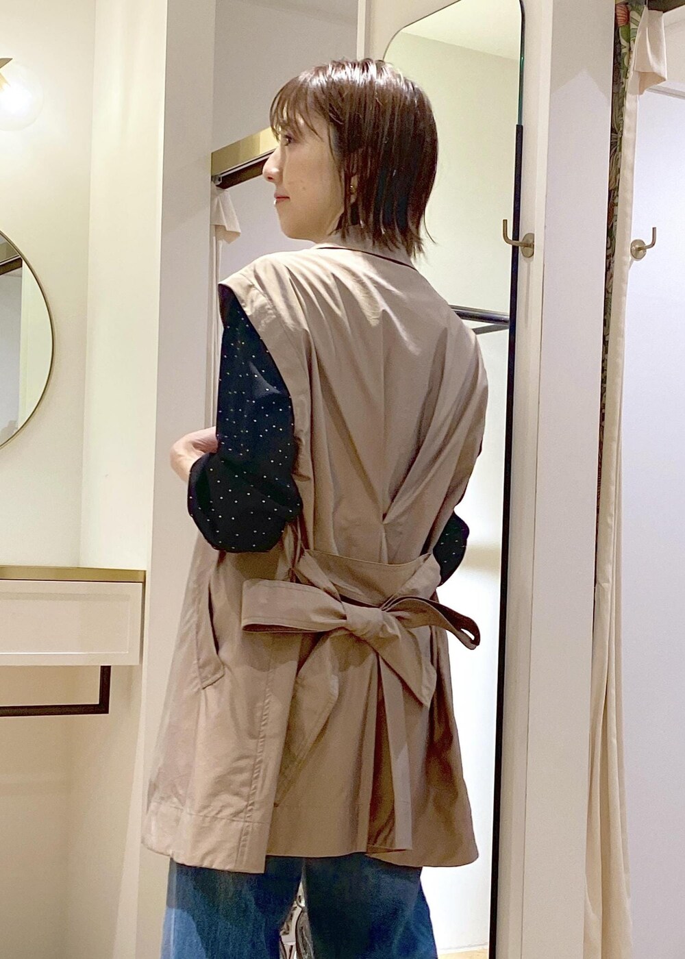 ブラック系のパンプス、グリーン系のトレンチコート、ブルー系のデニムパンツを着用したレディースの春コーディネートの4枚目の写真