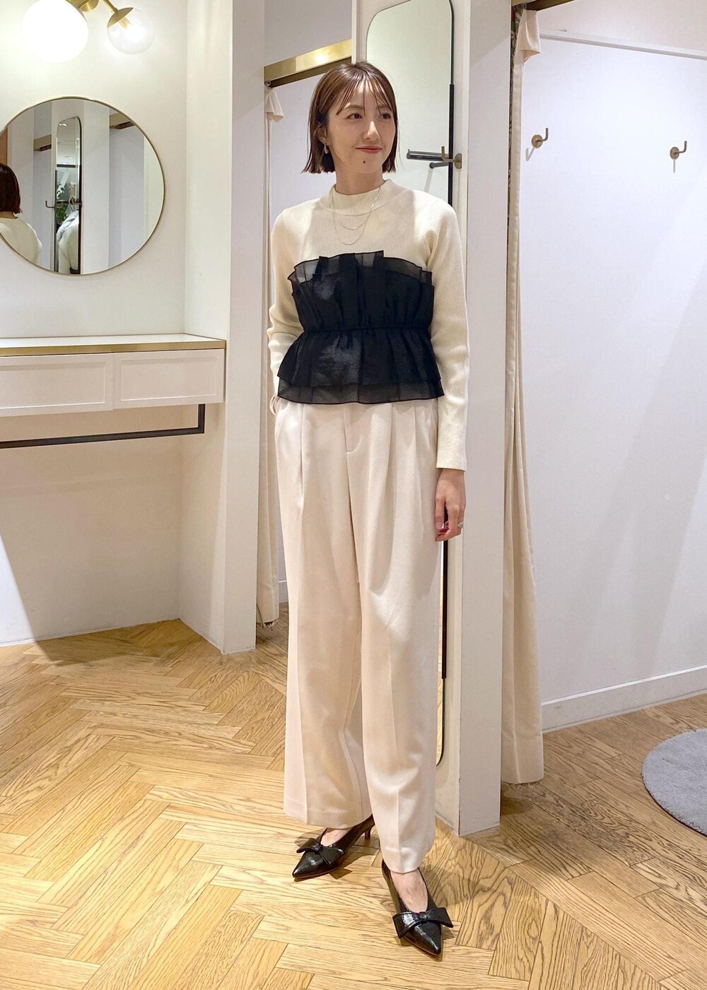 ブラック系のパンプス、ホワイト系のニット/セーター、ホワイト系のスラックスを着用したレディースの冬コーディネートの6枚目の写真