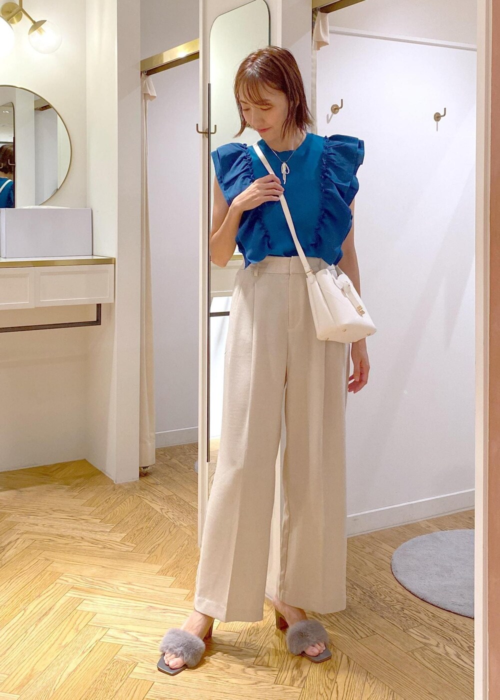 ホワイト系のスラックス、ホワイト系のショルダーバッグ、グレー系のドレスシューズを着用したレディースの夏コーディネートの4枚目の写真