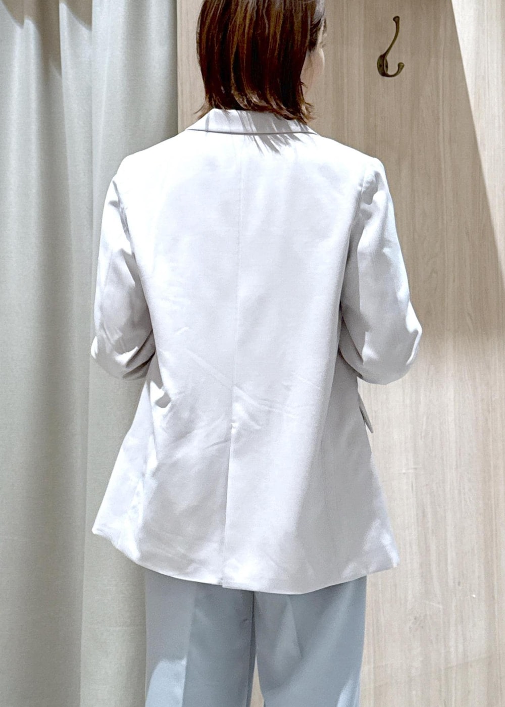 ブラック系のショルダーバッグ、ブルー系のスラックス、ベージュ系のテーラードジャケットを着用したレディースの春コーディネートの6枚目の写真