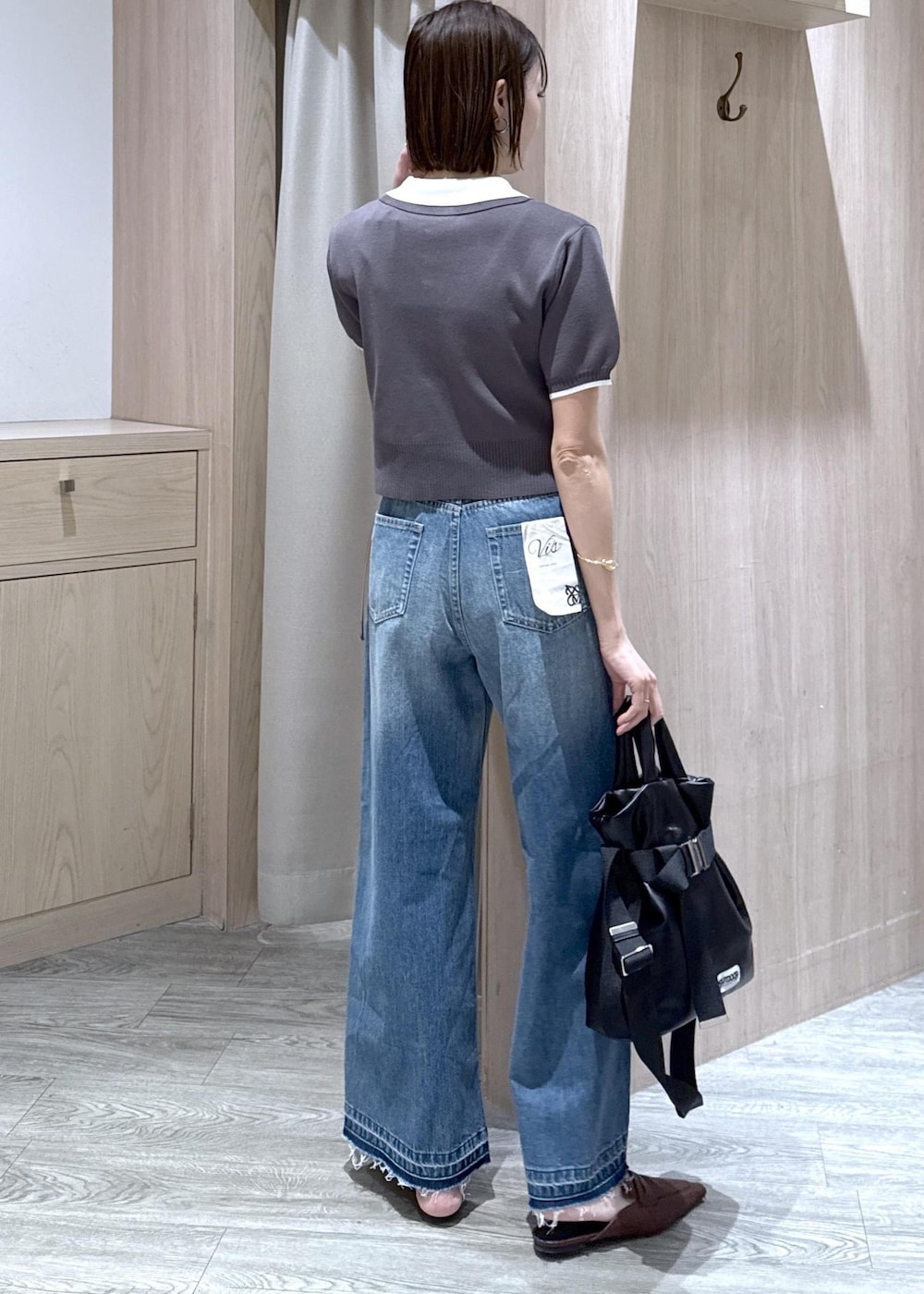 ホワイト系のキャミソール、ブラック系のトートバッグ、ブルー系のデニムパンツを着用したレディースの春コーディネートの2枚目の写真