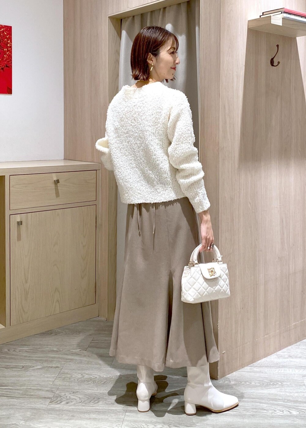 ホワイト系のブーツ、ベージュ系のスカート、ホワイト系のカーディガン/ボレロを着用したレディースの冬コーディネートの2枚目の写真