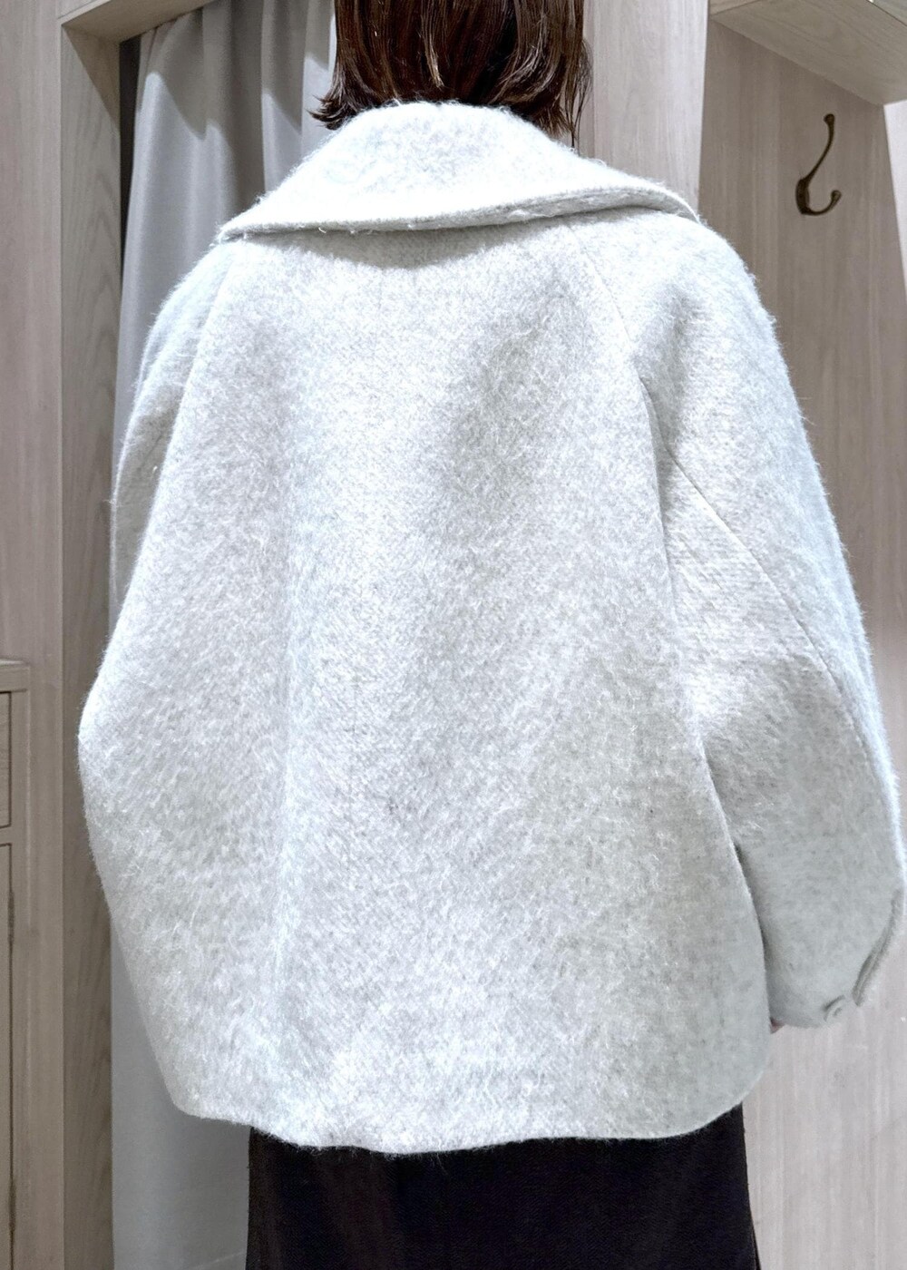 ブラウン系のショルダーバッグ、ブラック系のブーツ、ホワイト系のブルゾンを着用したレディースの秋コーディネートの7枚目の写真