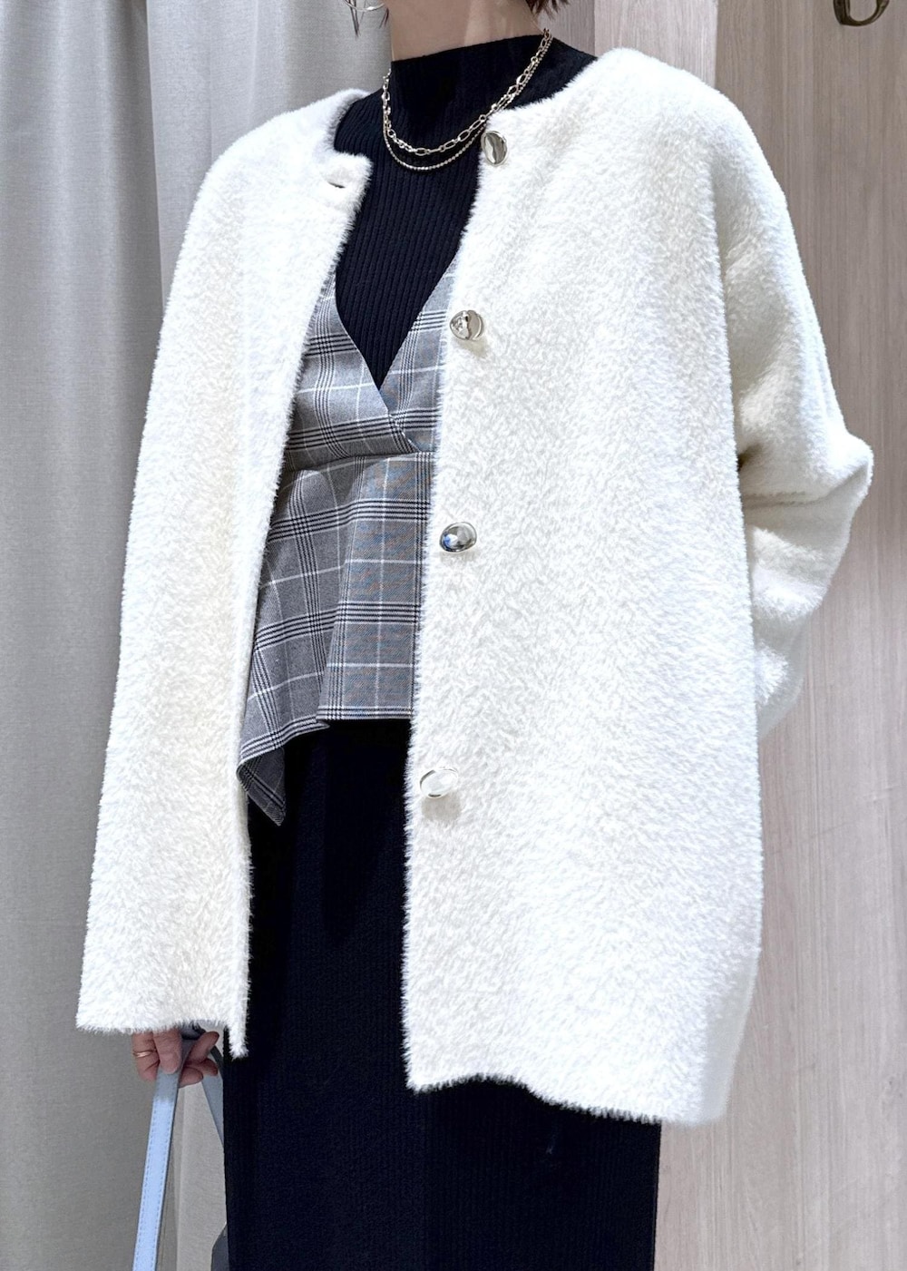 ブルー系のハンドバッグ、ホワイト系のノーカラージャケット、ブラック系のブーツを着用したレディースの秋コーディネートの9枚目の写真