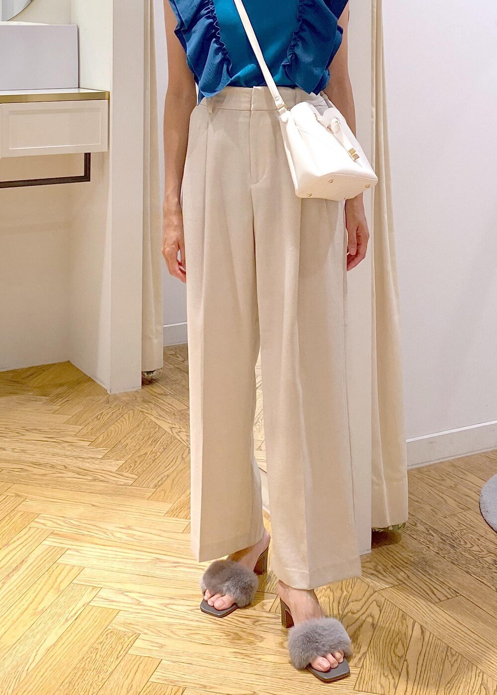 ホワイト系のスラックス、ホワイト系のショルダーバッグ、グレー系のドレスシューズを着用したレディースの夏コーディネートの7枚目の写真