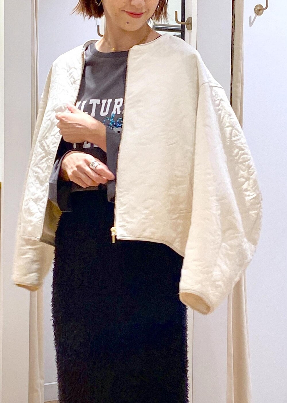 ホワイト系のブーツ、ブラック系のスカート、ホワイト系のブルゾンを着用したレディースの秋コーディネートの5枚目の写真