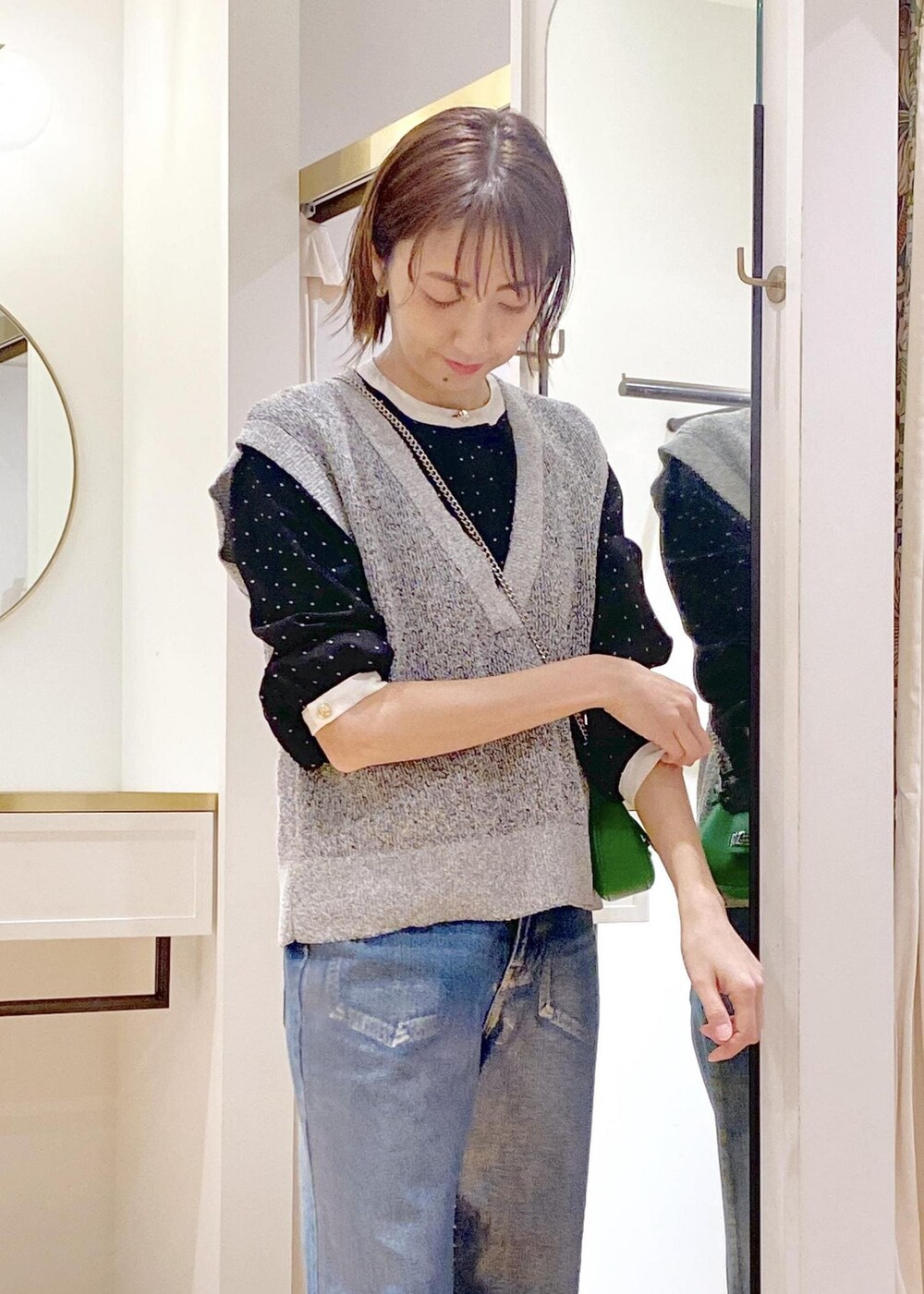 ブラック系のパンプス、ブルー系のデニムパンツ、ブラック系のベストを着用したレディースの春コーディネートの3枚目の写真