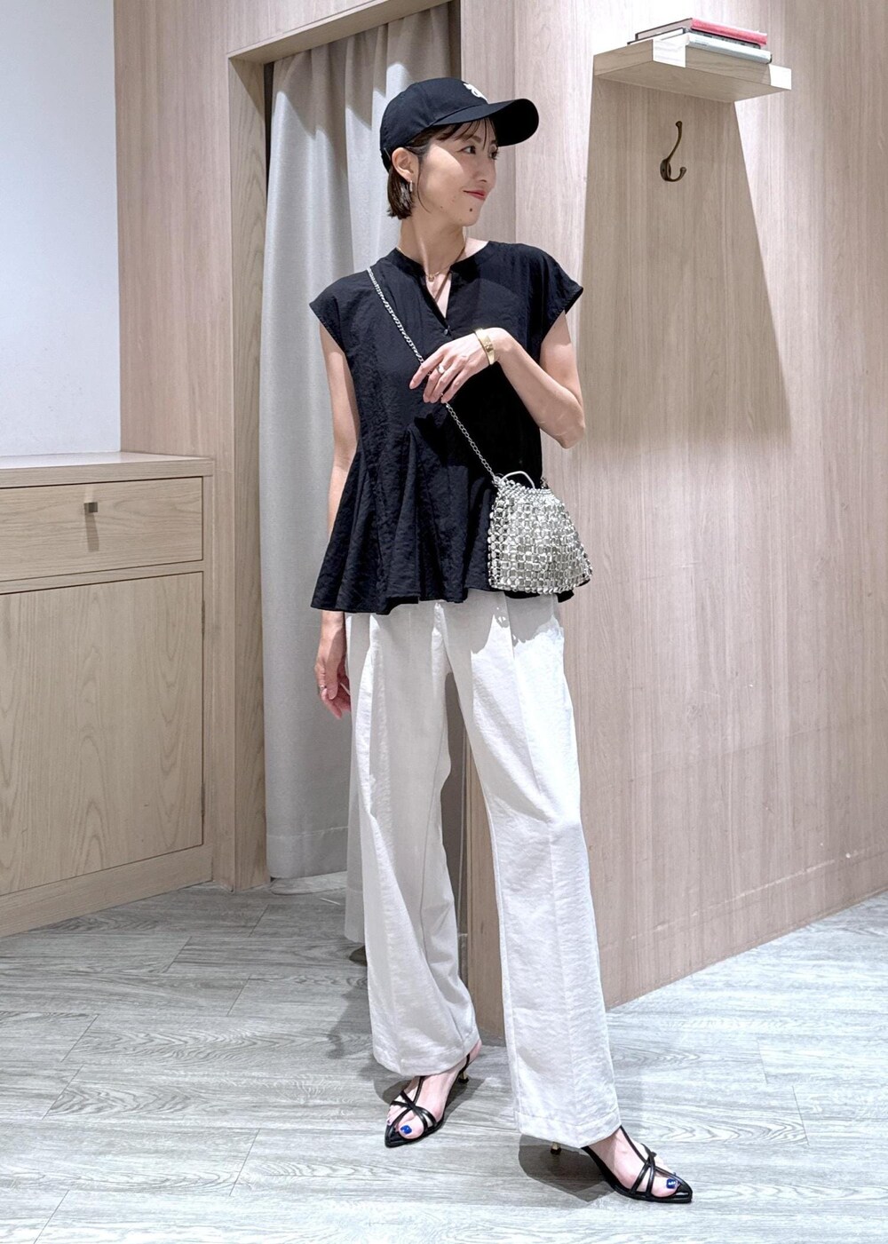 ブラック系のサンダル、ブラック系のシャツ/ブラウス、ホワイト系のスラックスを着用したレディースの夏コーディネートの2枚目の写真