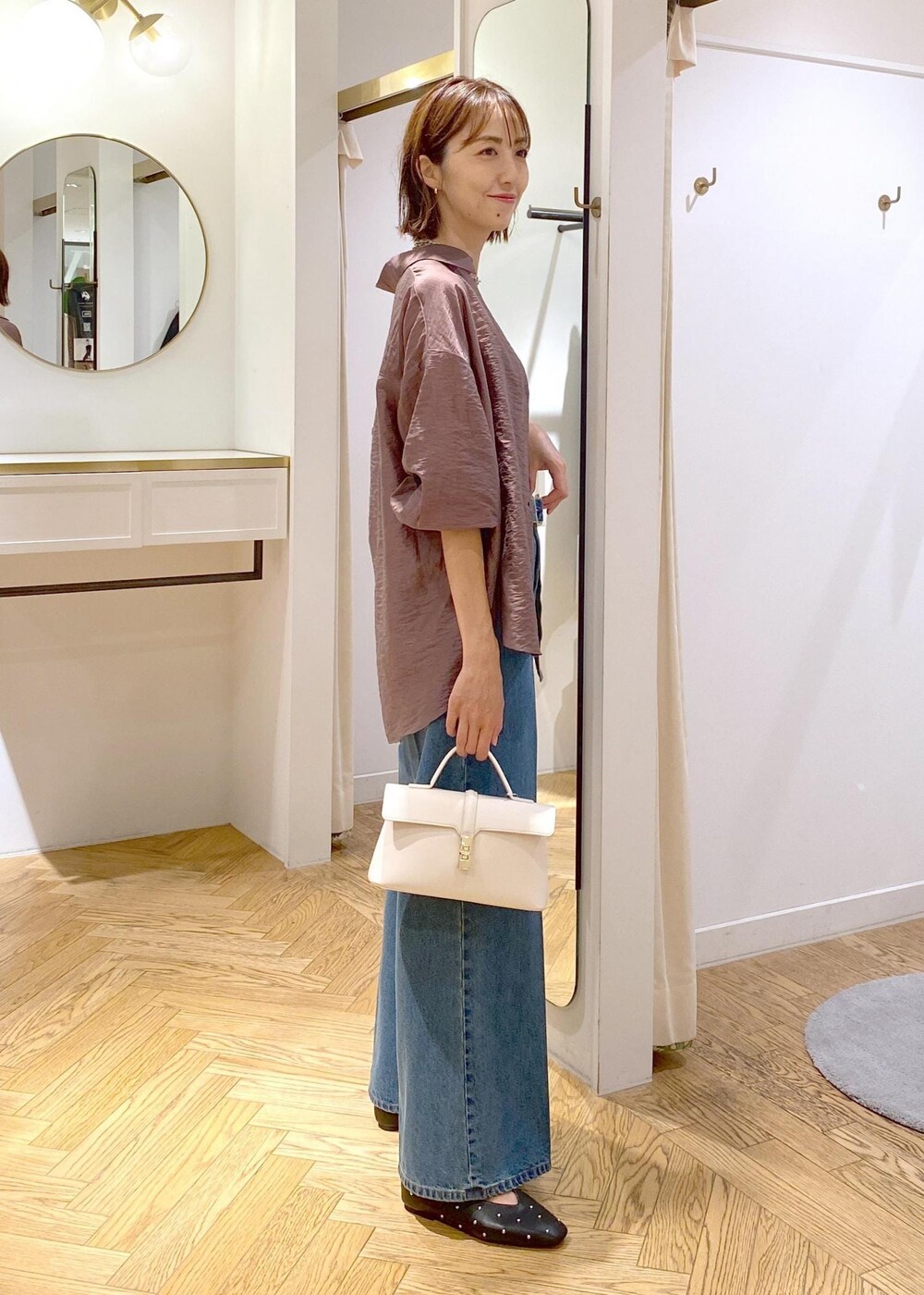 ブラック系のキャミソール、ホワイト系のショルダーバッグ、ブルー系のデニムパンツを着用したレディースの秋コーディネートの4枚目の写真