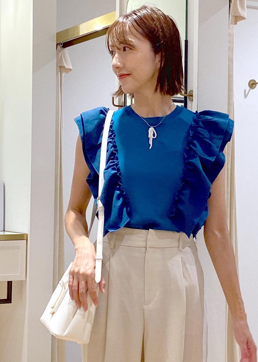 ホワイト系のスラックス、ホワイト系のショルダーバッグ、グレー系のドレスシューズを着用したレディースの夏コーディネートの8枚目の写真