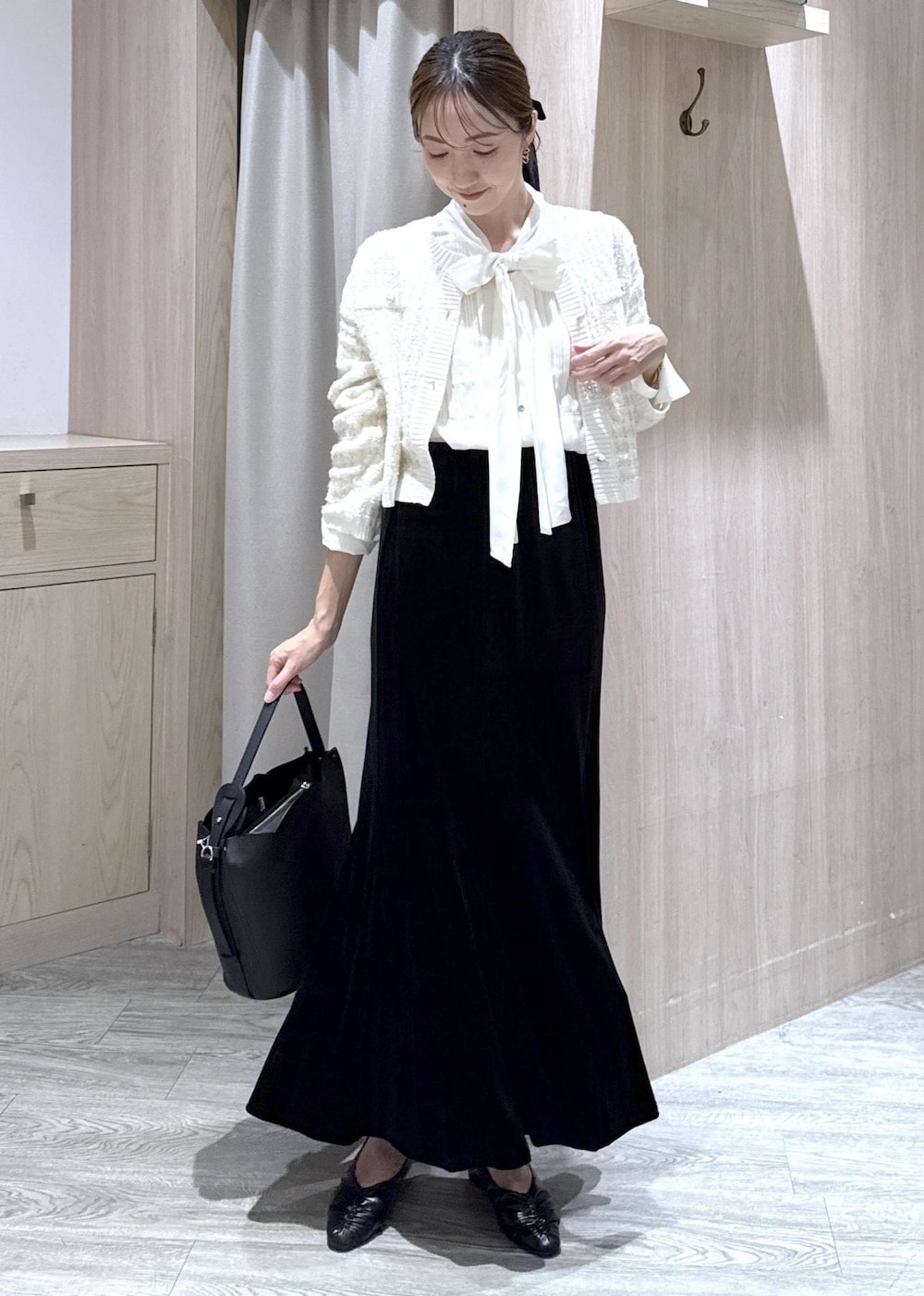 ブラック系のパンプス、ホワイト系のカーディガン/ボレロ、ブラック系のショルダーバッグを着用したレディースの秋コーディネートの2枚目の写真