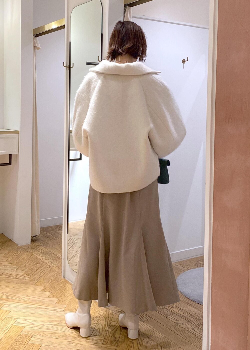 ホワイト系のブーツ、ベージュ系のスカート、ホワイト系のその他アウターを着用したレディースの秋コーディネートの2枚目の写真