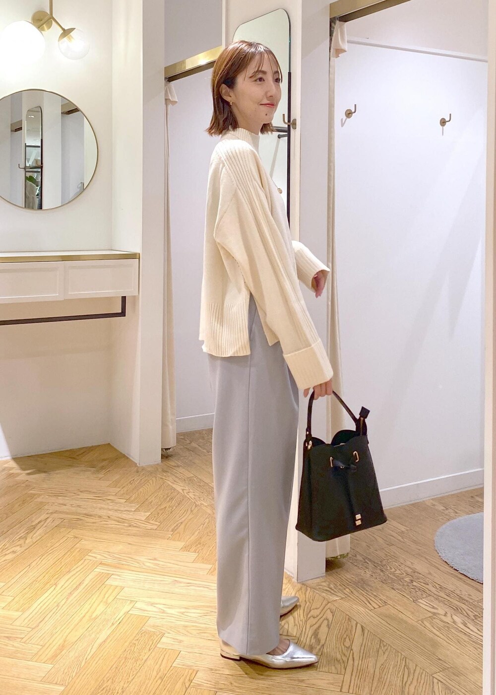 シルバー系のパンプス、ブラック系のショルダーバッグ、ブルー系のスラックスを着用したレディースの秋コーディネートの2枚目の写真