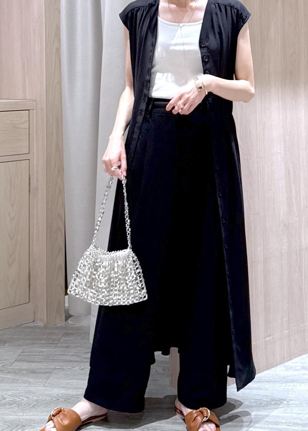 ホワイト系のタンクトップ、ブラック系のスラックス、シルバー系のハンドバッグを着用したレディースの春コーディネートの6枚目の写真