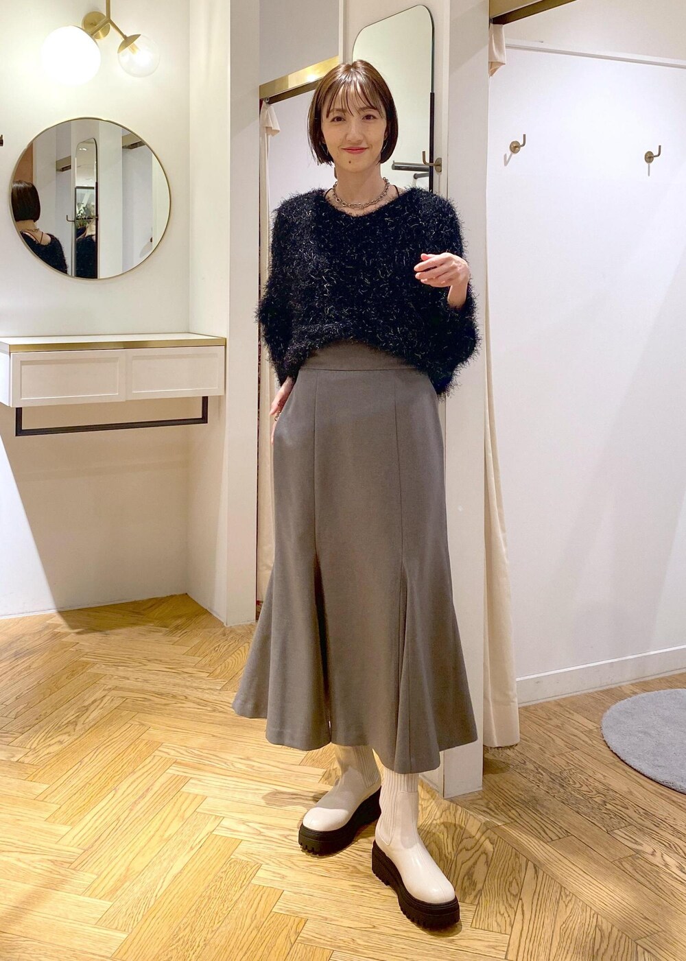 ホワイト系のブーツ、グレー系のスカート、ホワイト系のダウンジャケット/コートを着用したレディースの冬コーディネートの7枚目の写真