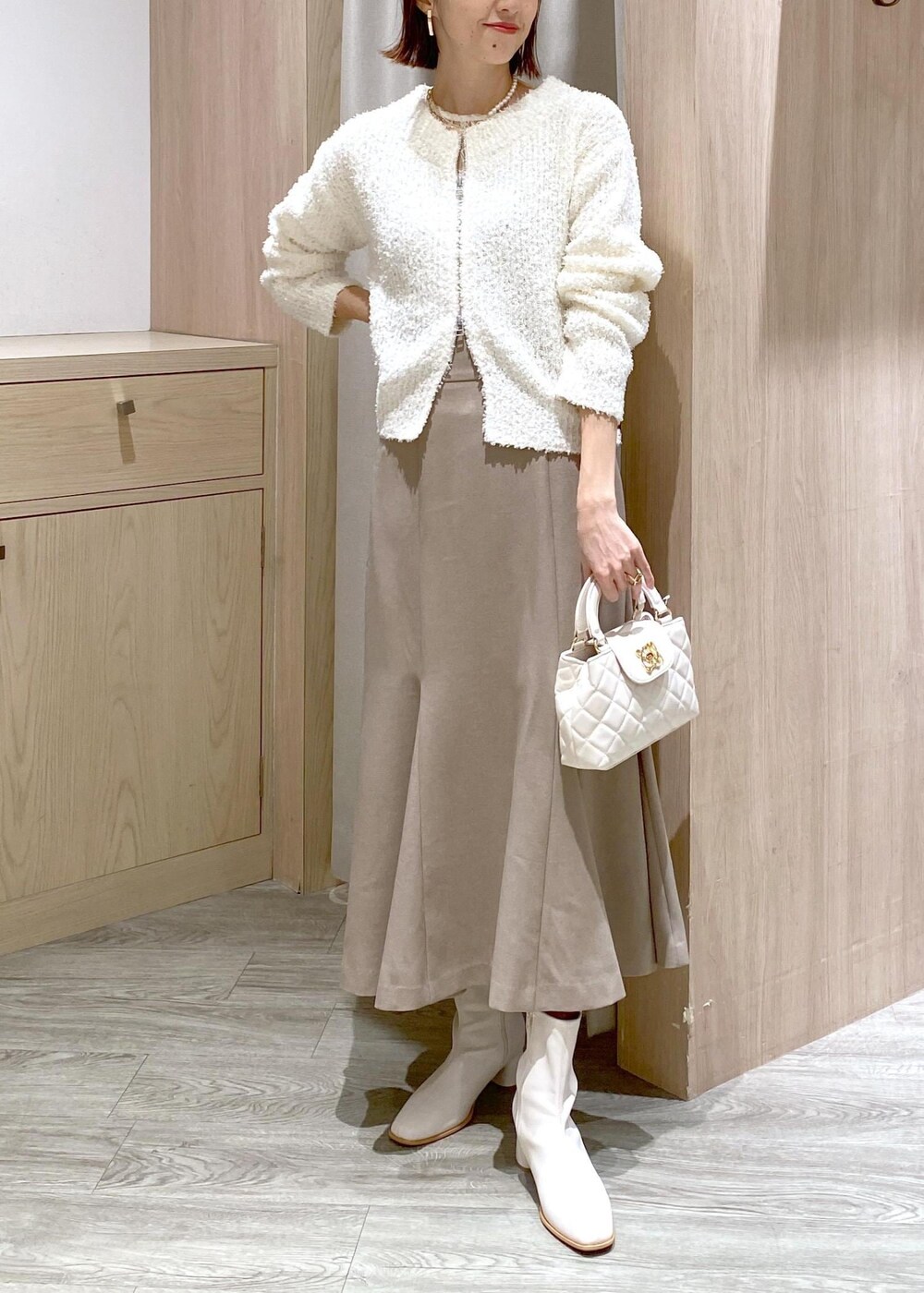 ホワイト系のブーツ、ベージュ系のスカート、ホワイト系のカーディガン/ボレロを着用したレディースの冬コーディネートの4枚目の写真