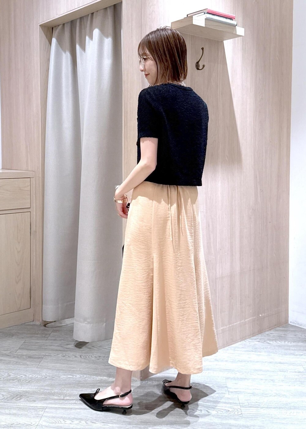 ブラック系のパンプス、オレンジ系のスカート、ブラック系のハンドバッグを着用したレディースの春コーディネートの4枚目の写真