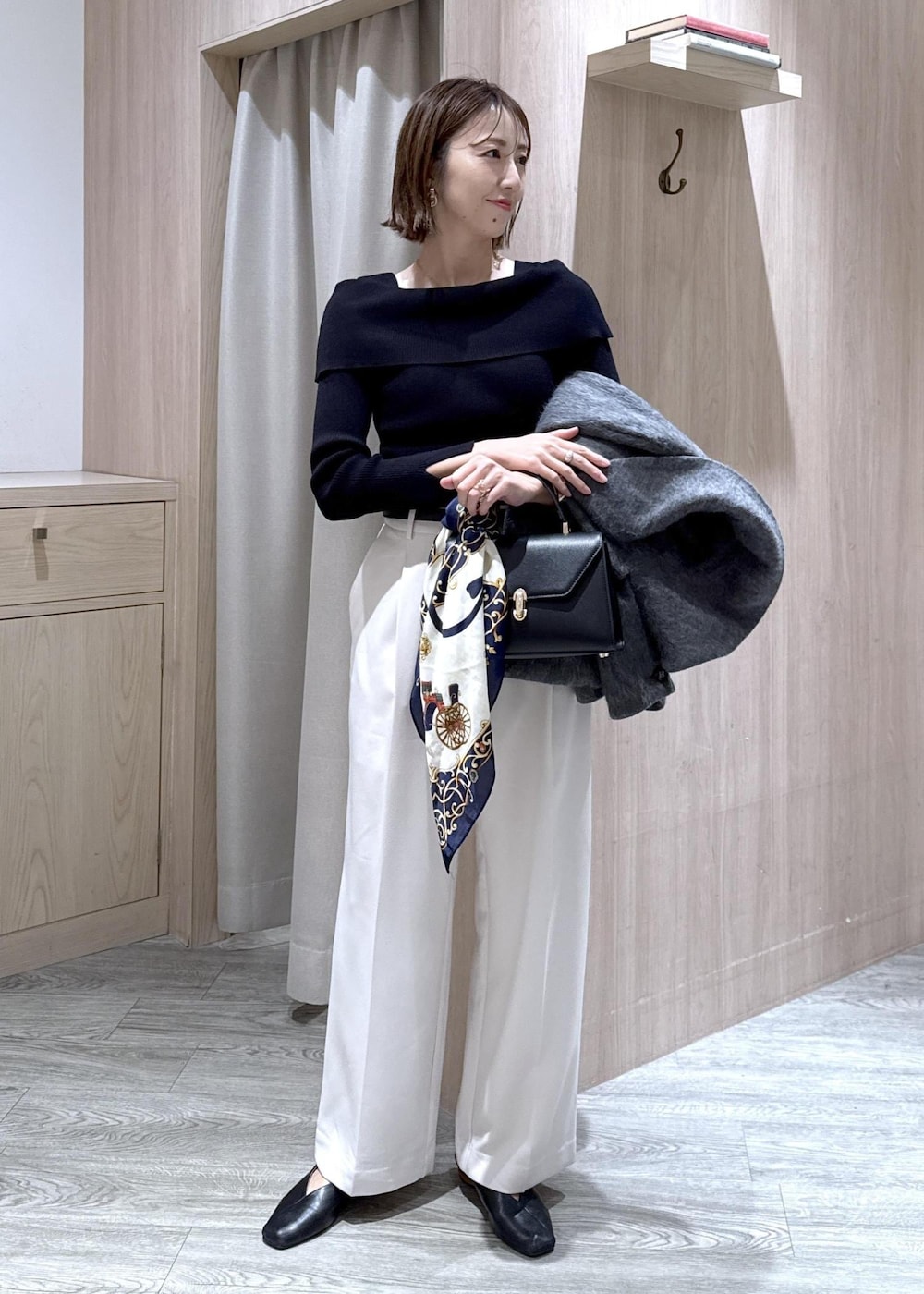 ブラック系のニット/セーター、グレー系のブルゾン、ブラック系のハンドバッグを着用したレディースの冬コーディネートの2枚目の写真