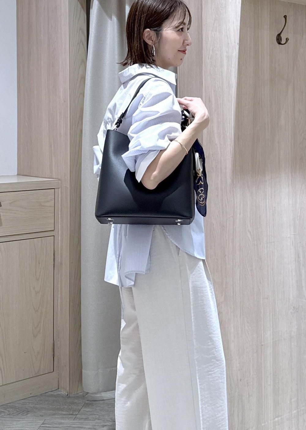 ベージュ系のキャミソール、ブラック系のショルダーバッグ、ブルー系のシャツ/ブラウスを着用したレディースの春コーディネートの4枚目の写真