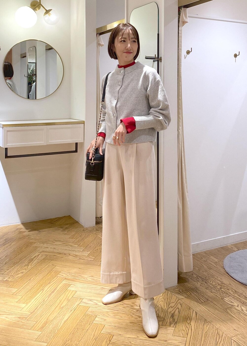 ホワイト系のブーツ、グレー系のカーディガン/ボレロ、レッド系のニット/セーターを着用したレディースの冬コーディネートの2枚目の写真