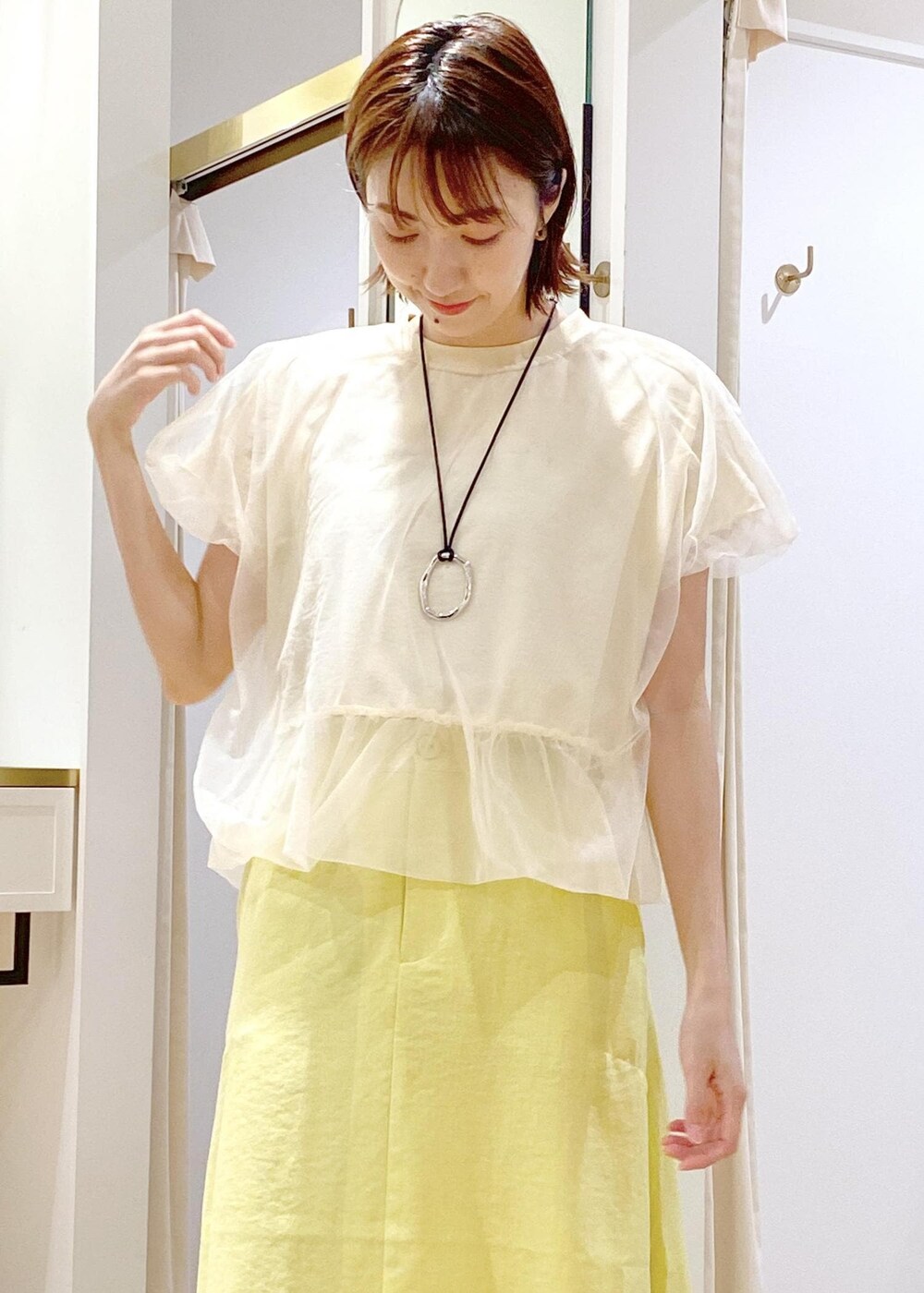 ブラック系のショルダーバッグ、ブラック系のサンダル、イエロー系のスカートを着用したレディースの春コーディネートの3枚目の写真