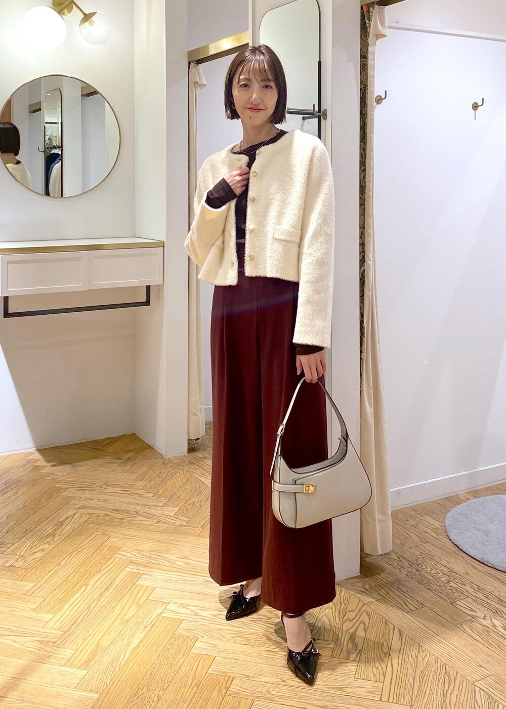 ホワイト系のハンドバッグ、ブラック系のパンプス、ブラウン系のその他パンツを着用したレディースの冬コーディネートの2枚目の写真