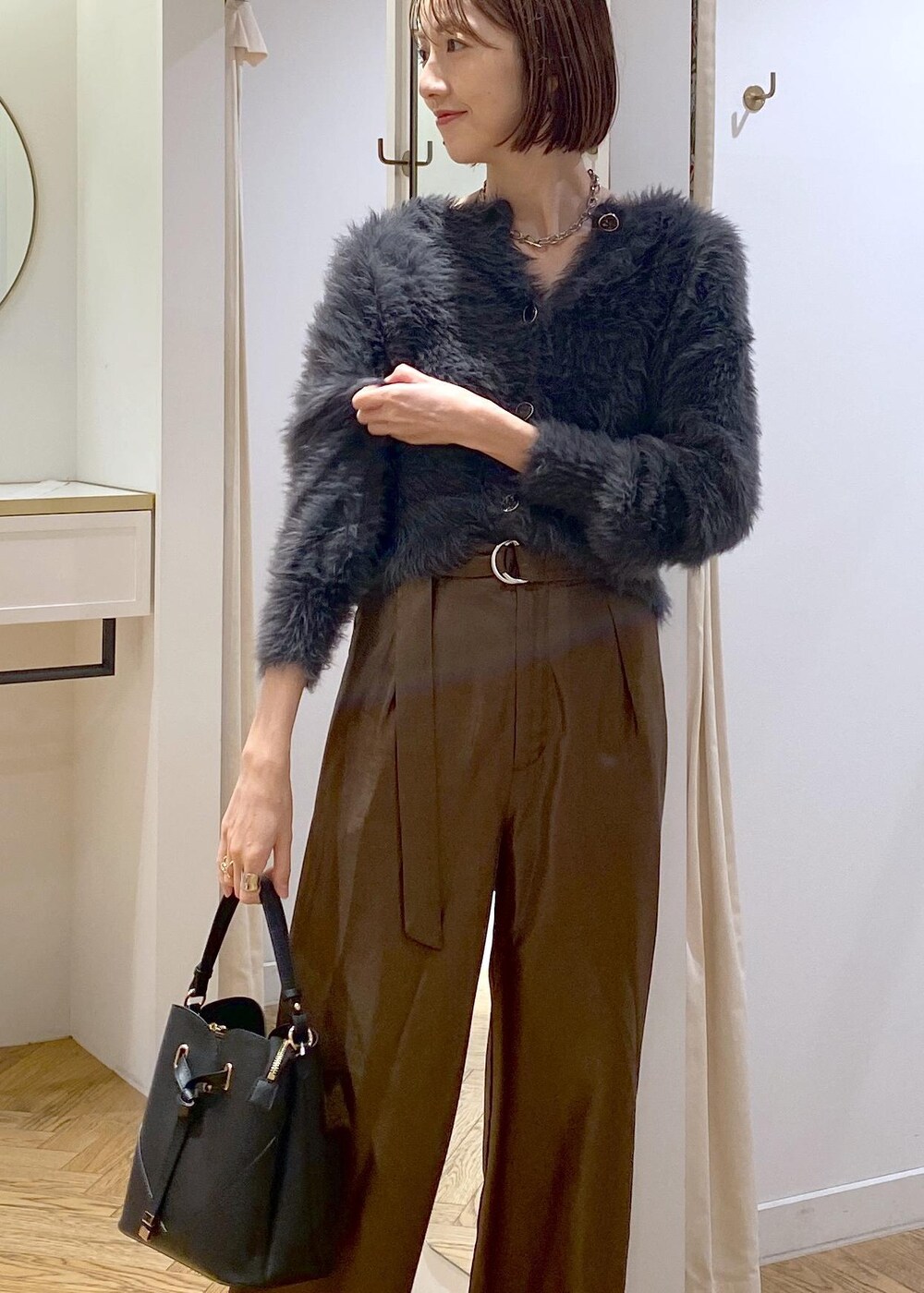 ブラック系のショルダーバッグ、ブラック系のブーツ、グレー系のカーディガン/ボレロを着用したレディースの冬コーディネートの5枚目の写真