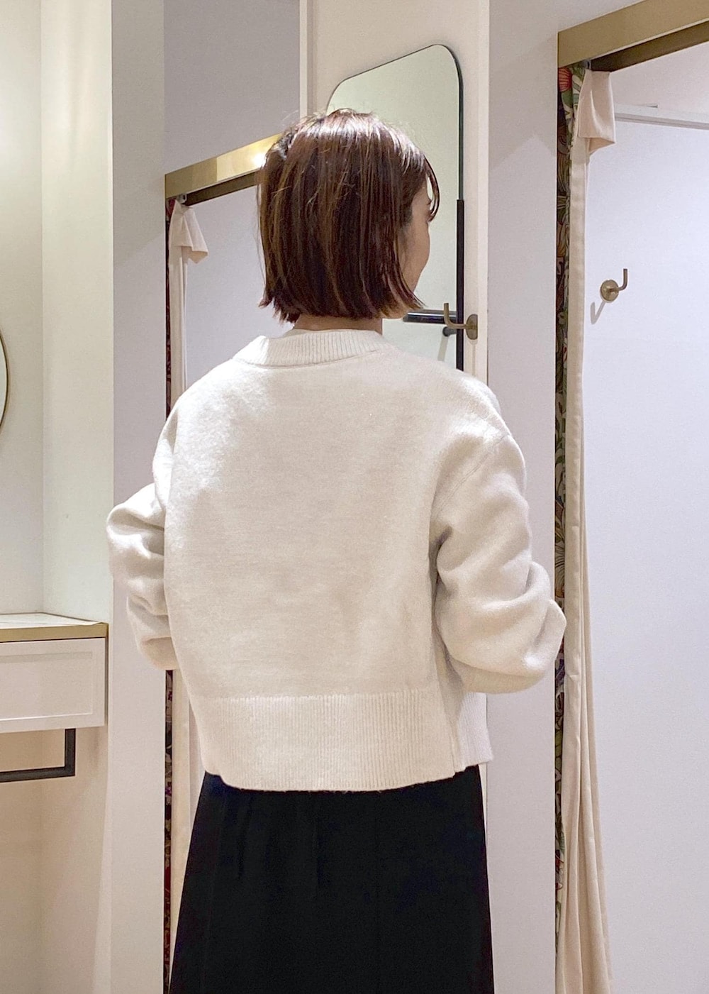 ホワイト系のカーディガン/ボレロ、ブラック系のスカート、ブラック系のパンプスを着用したレディースの冬コーディネートの8枚目の写真