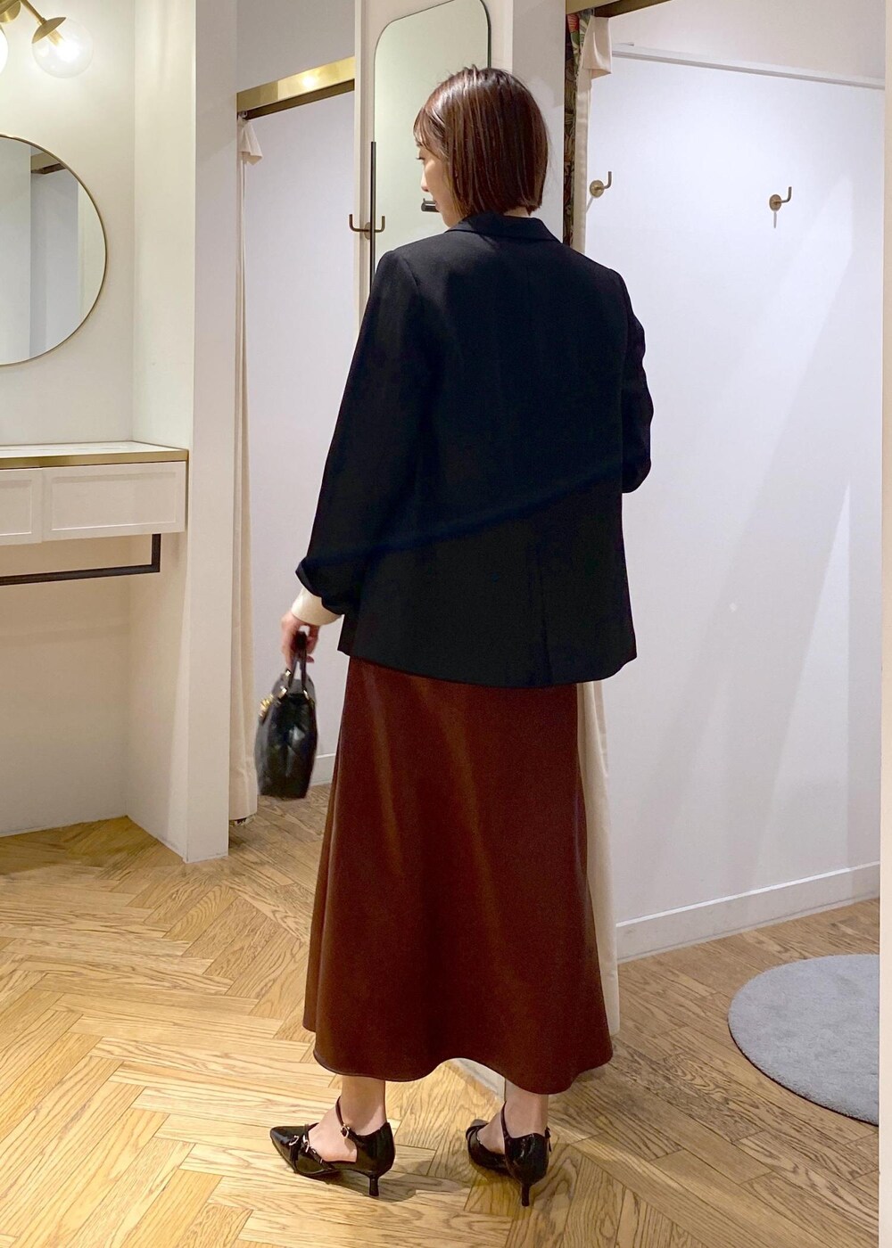 ブラック系のテーラードジャケット、ブラック系のパンプス、ブラウン系のスカートを着用したレディースの冬コーディネートの4枚目の写真