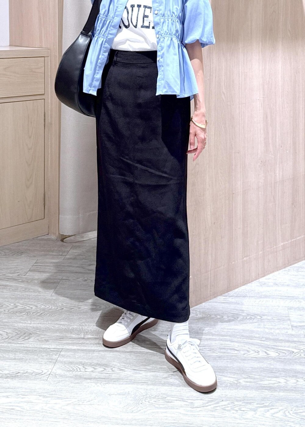 ブラック系のショルダーバッグ、ブラック系のスカート、ホワイト系のTシャツ/カットソーを着用したレディースの春コーディネートの6枚目の写真