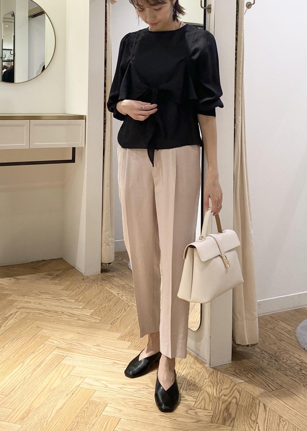 ブラック系のパンプス、ホワイト系のハンドバッグ、ブラック系のシャツ/ブラウスを着用したレディースの春コーディネートの4枚目の写真