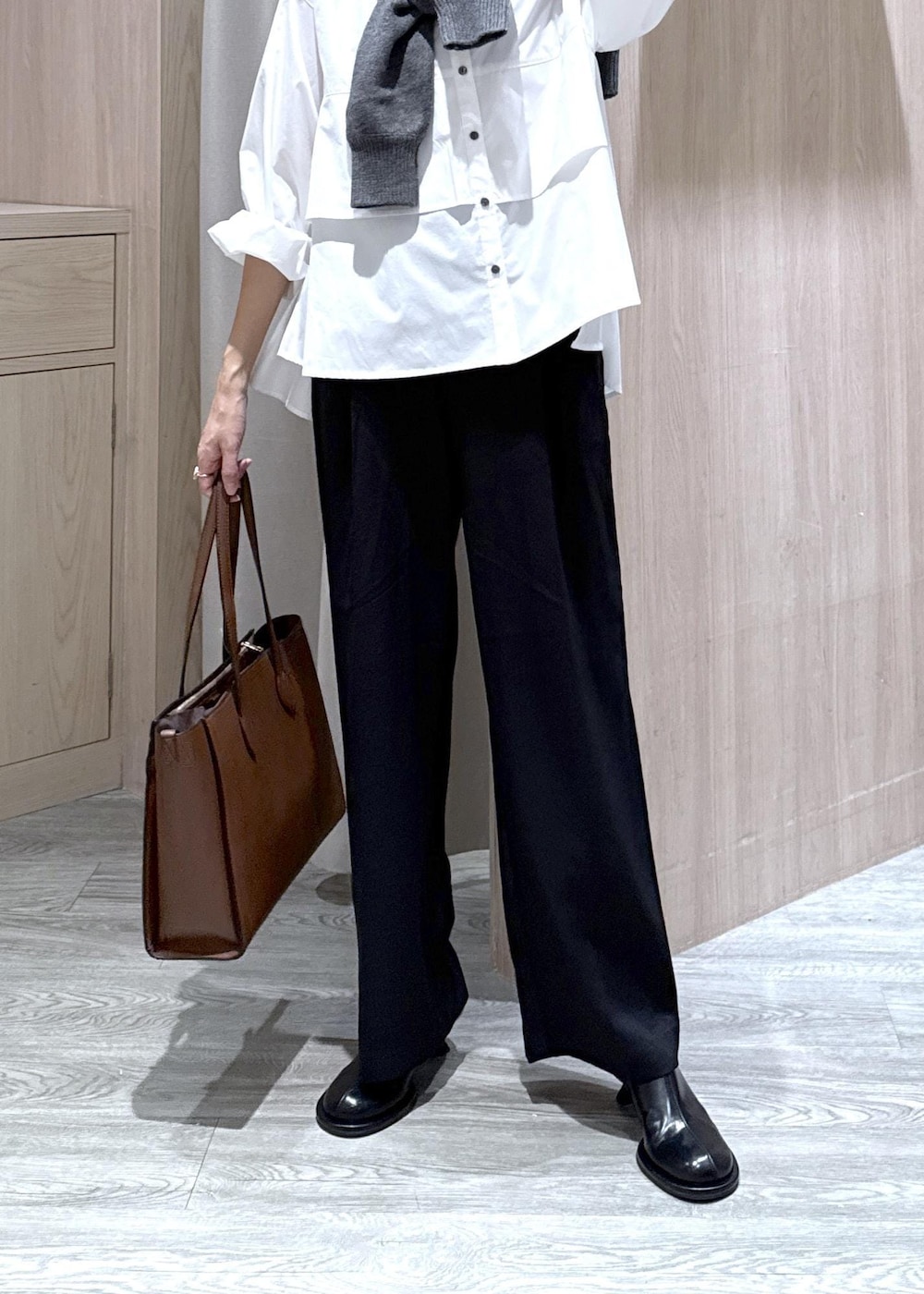 ブラウン系のトートバッグ、ホワイト系のシャツ/ブラウス、ブラック系のスラックスを着用したレディースの秋コーディネートの6枚目の写真