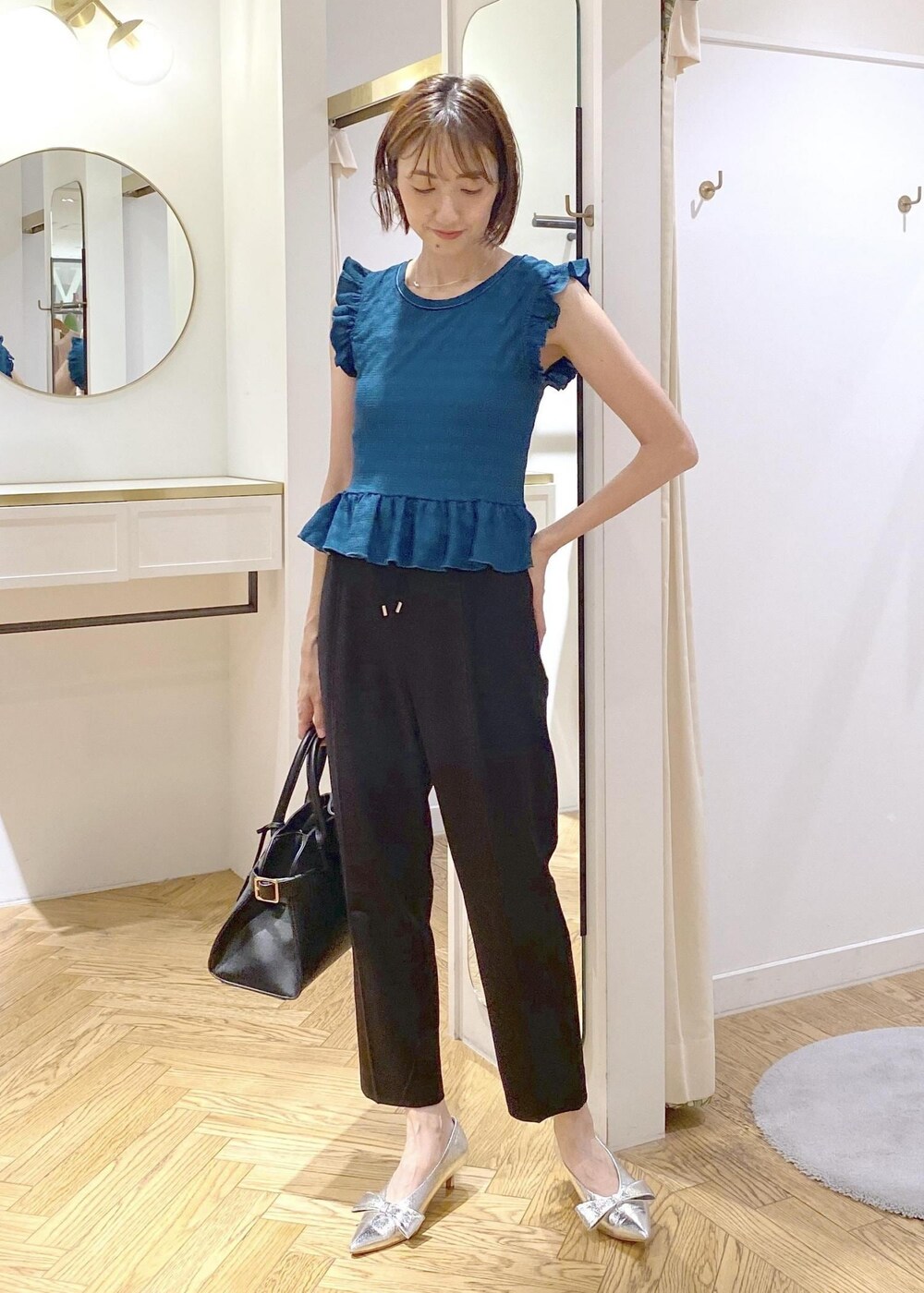 シルバー系のパンプス、ブラック系のスラックス、ブラック系のキャミソールを着用したレディースの夏コーディネートの2枚目の写真