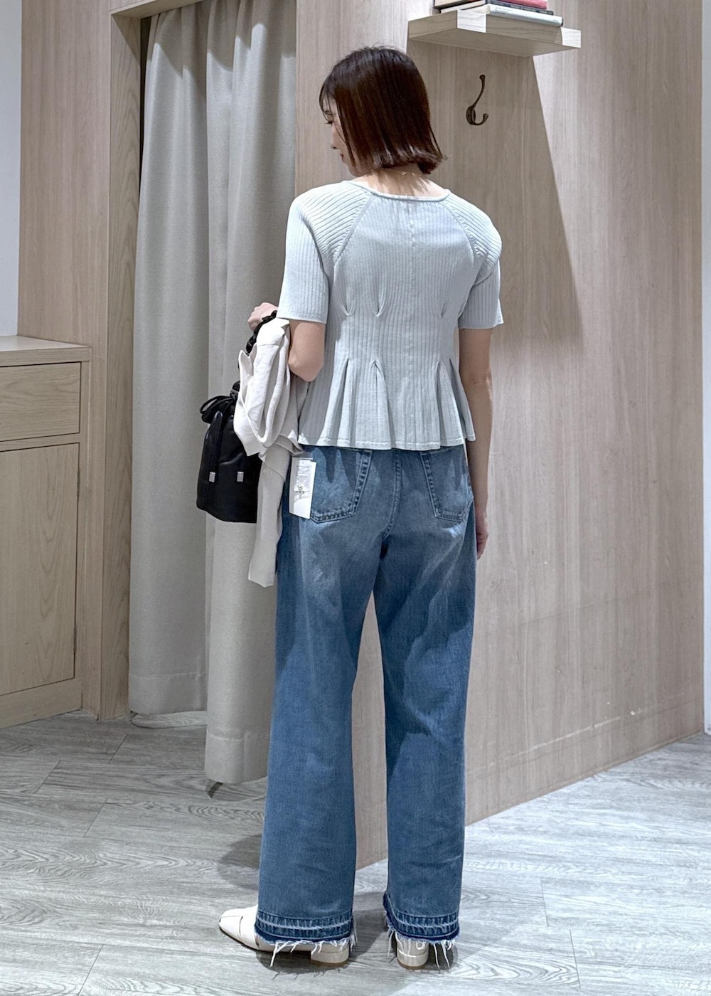 ブルー系のデニムパンツ、ホワイト系のパンプス、ブラック系のショルダーバッグを着用したレディースの春コーディネートの4枚目の写真