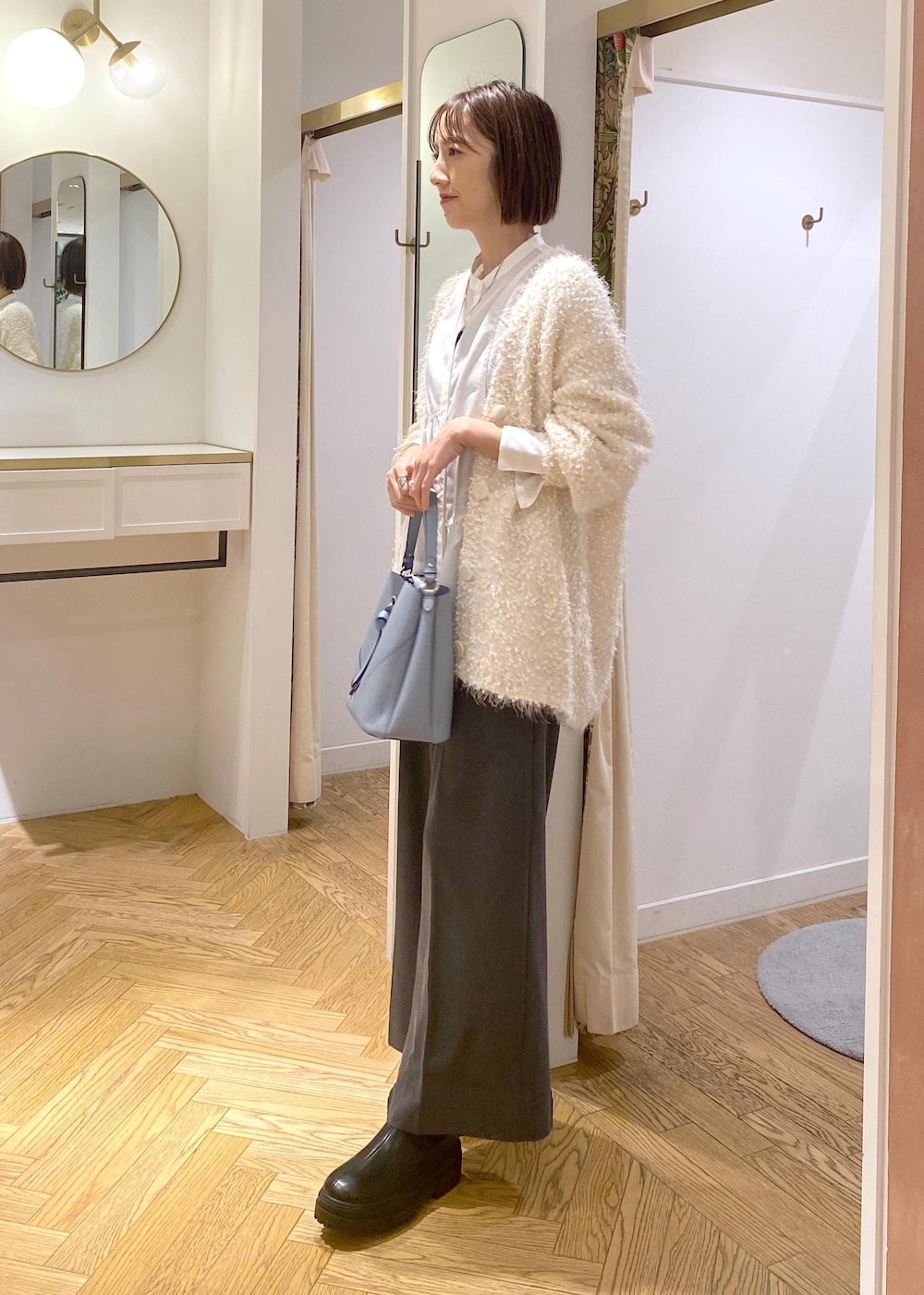 ブラック系のブーツ、ホワイト系のカーディガン/ボレロ、ホワイト系のシャツ/ブラウスを着用したレディースの冬コーディネートの2枚目の写真