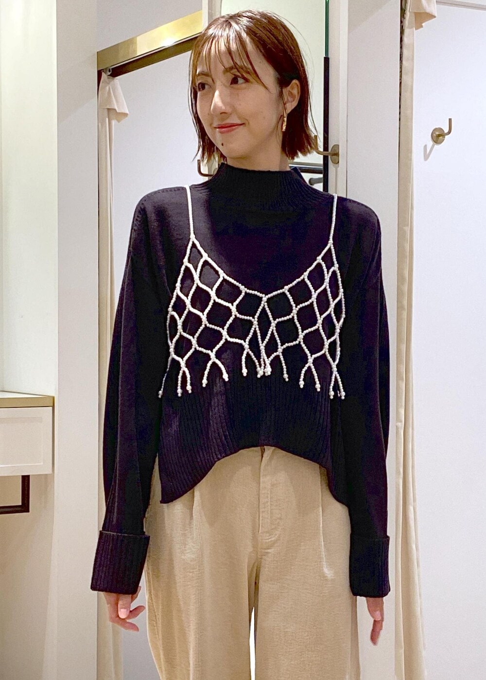 ブラック系のショルダーバッグ、ホワイト系のキャミソール、ベージュ系のスラックスを着用したレディースの秋コーディネートの6枚目の写真