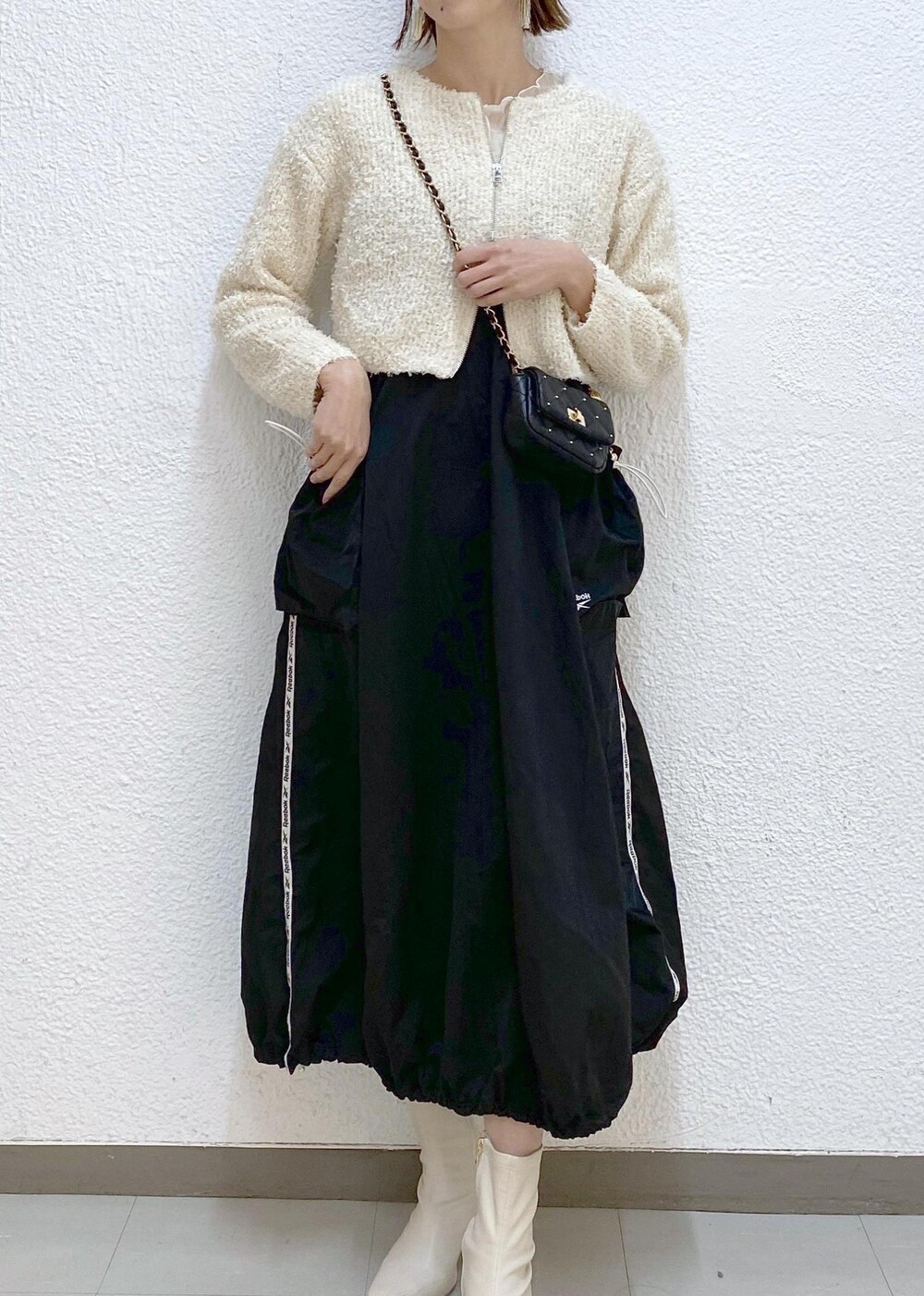 ホワイト系のTシャツ/カットソー、ブラック系のショルダーバッグ、ホワイト系のカーディガン/ボレロを着用したレディースの冬コーディネートの3枚目の写真