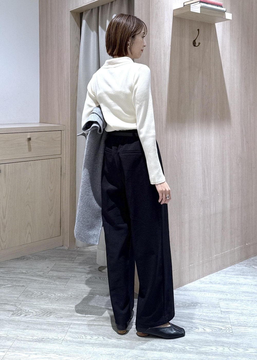 ホワイト系のニット/セーター、グレー系のその他アウター、ブラック系のスラックスを着用したレディースの冬コーディネートの6枚目の写真