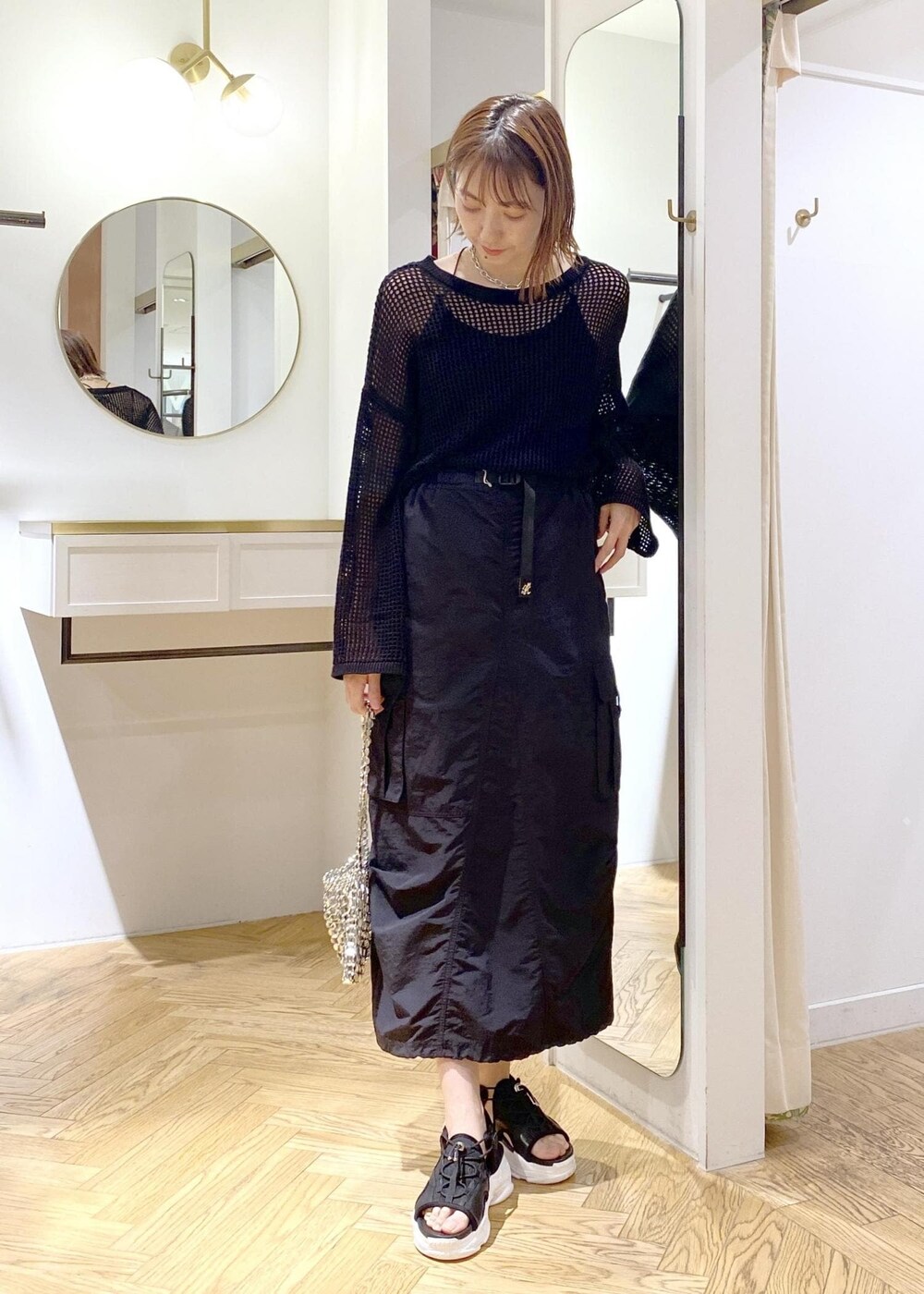 シルバー系のショルダーバッグ、ブラック系のスカート、ブラック系のニット/セーターを着用したレディースの春コーディネートの3枚目の写真