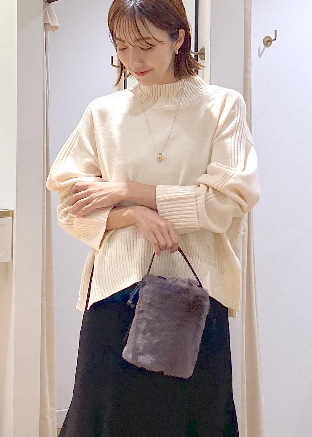 ブラック系のスカート、ホワイト系のニット/セーター、グレー系のショルダーバッグを着用したレディースの秋コーディネートの5枚目の写真