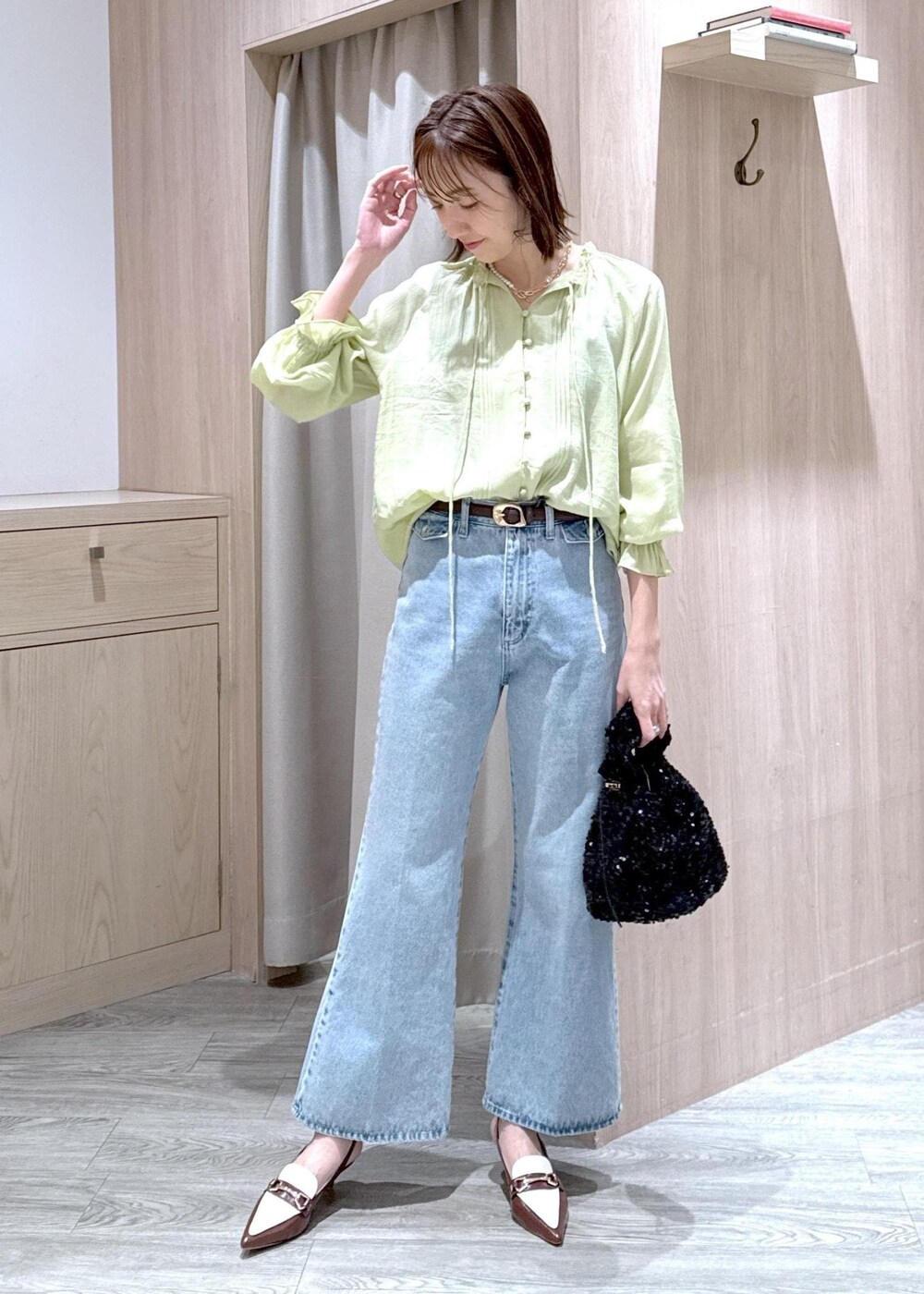 ブルー系のデニムパンツ、ブラウン系のパンプス、ブラック系のハンドバッグを着用したレディースの春コーディネートの2枚目の写真