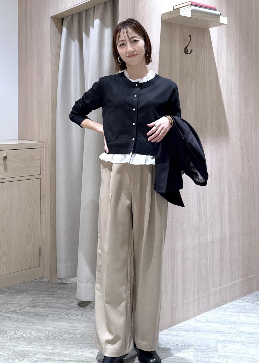 ブラック系のショルダーバッグ、ベージュ系のスラックス、ブラック系のテーラードジャケットを着用したレディースの冬コーディネートの5枚目の写真