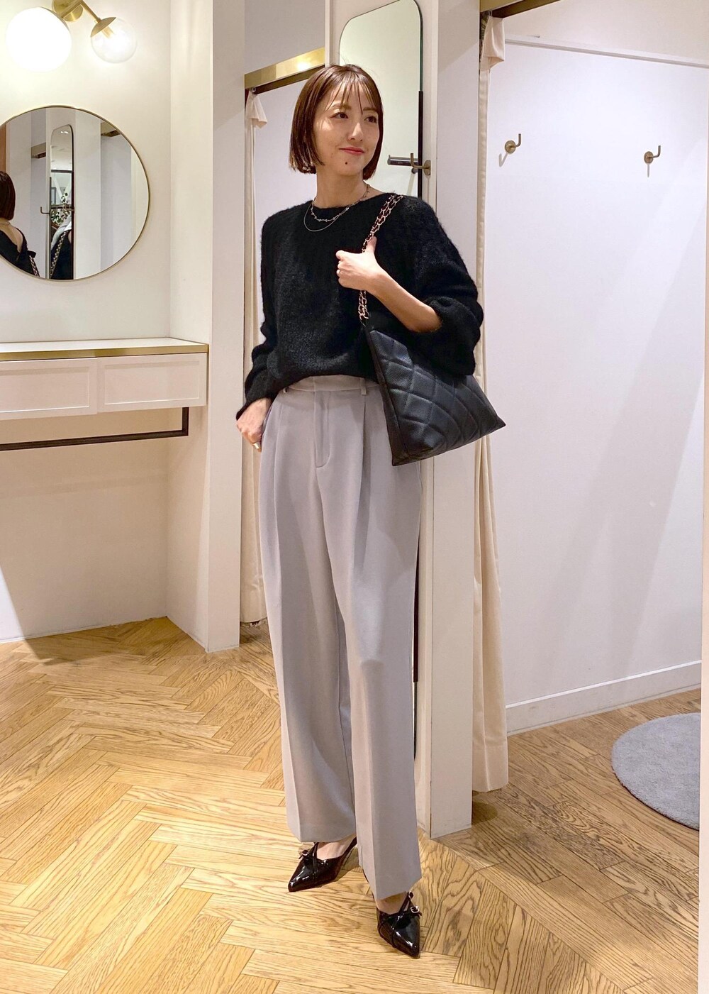 ブルー系のスラックス、ブラック系のパンプス、ブラック系のショルダーバッグを着用したレディースの冬コーディネートの9枚目の写真