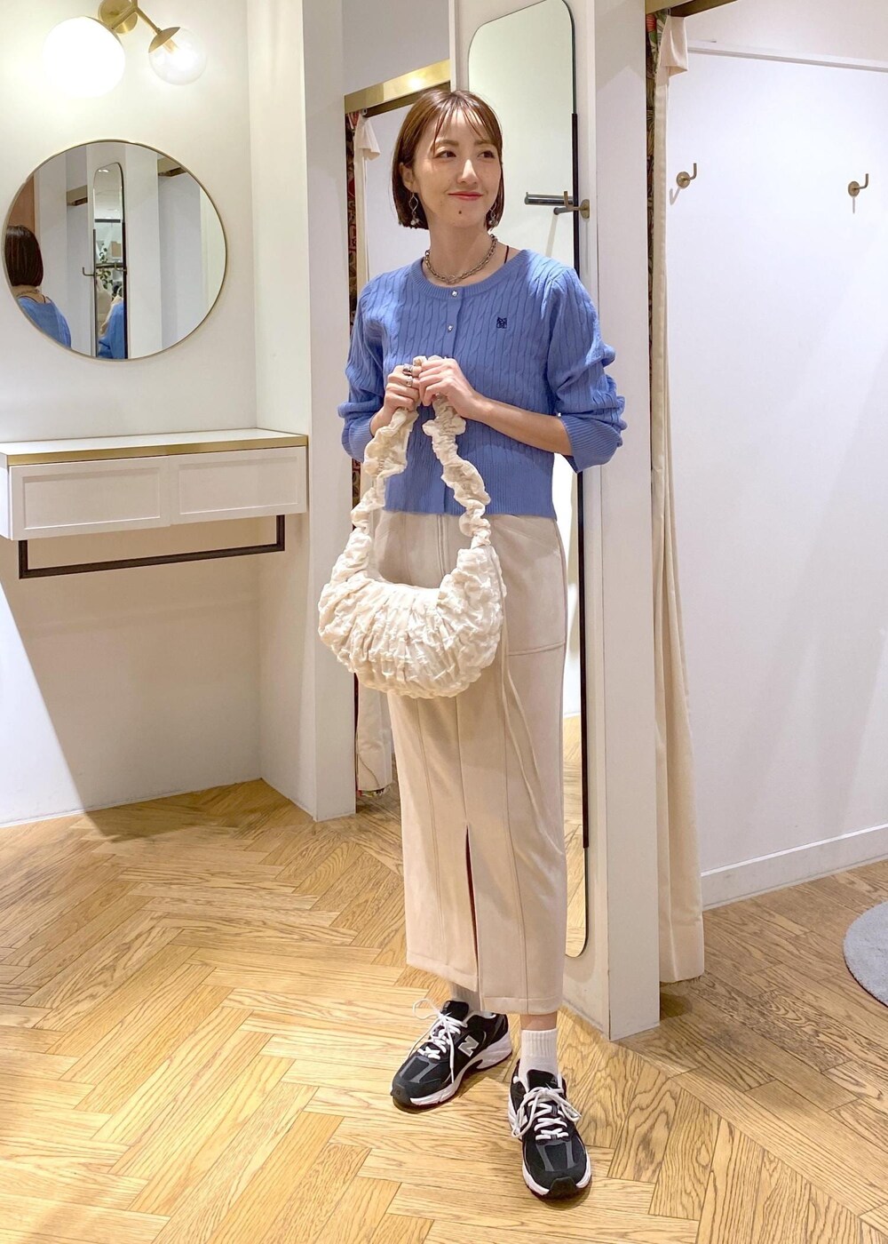 ホワイト系のショルダーバッグ、ブルー系のカーディガン/ボレロ、ベージュ系のスカートを着用したレディースの冬コーディネートの2枚目の写真