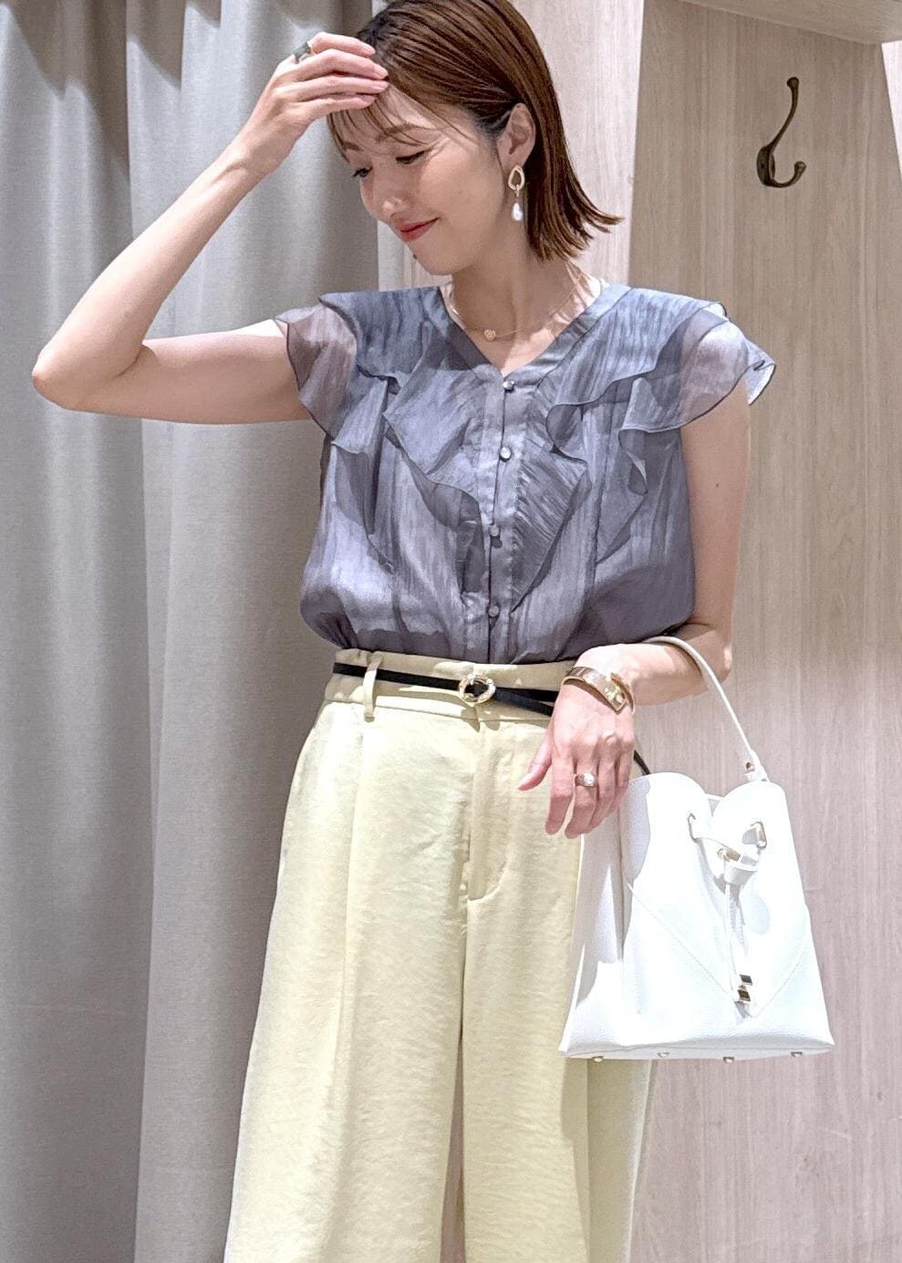 ホワイト系のショルダーバッグ、ホワイト系のサンダル、イエロー系のスラックスを着用したレディースの夏コーディネートの6枚目の写真